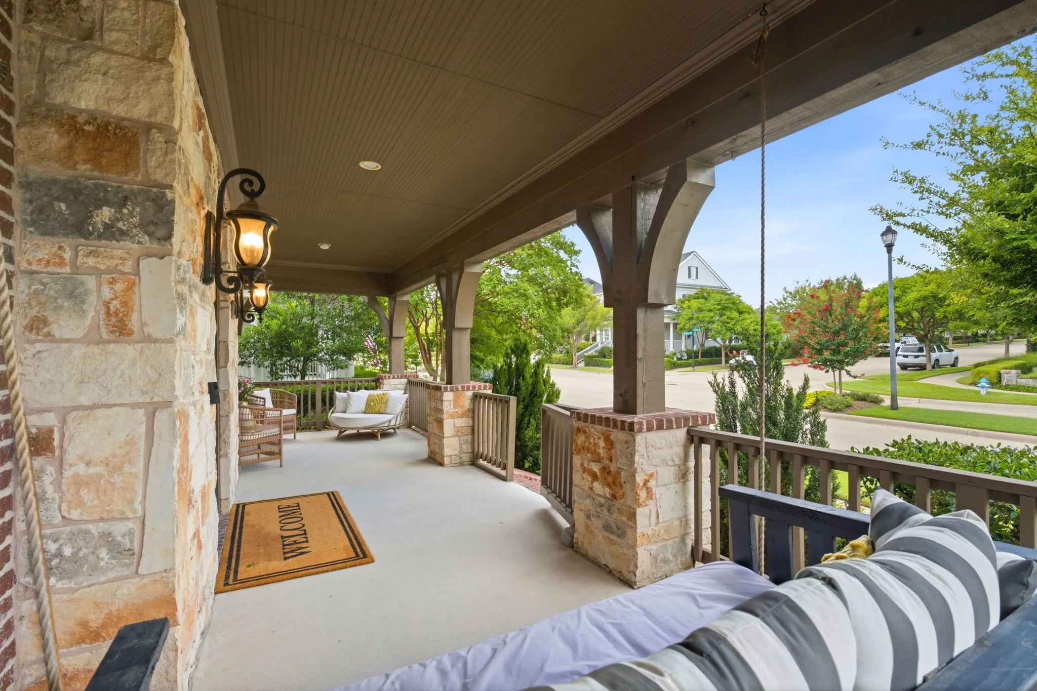 Another view of this inviting spacious front porch featuring, covered seating area that provides the perfect space for relaxing outdoors while staying protected from the elements, making it an ideal spot for morning coffee or evening entertaining. Look at the gorgeous landscaping through the neighborhood