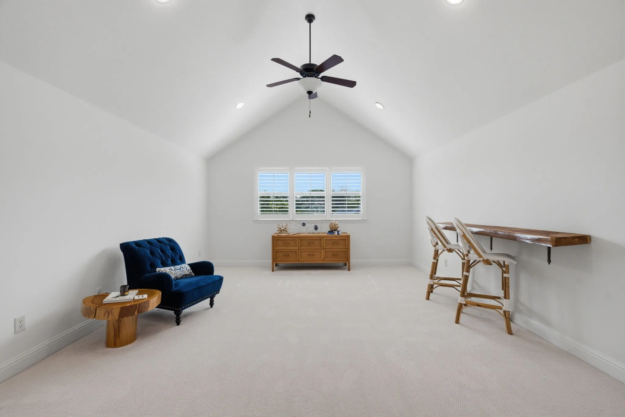 Spacious and inviting game room featuring stunning vaulted ceilings, windows that allow for plenty of natural light, and an overhead ceiling fan for comfort. This highly versatile area offers enough square footage to easily accommodate a pool table, gaming setups, or a dedicated home hobby space, and it is conveniently situated right next to the media room for seamless flow.
