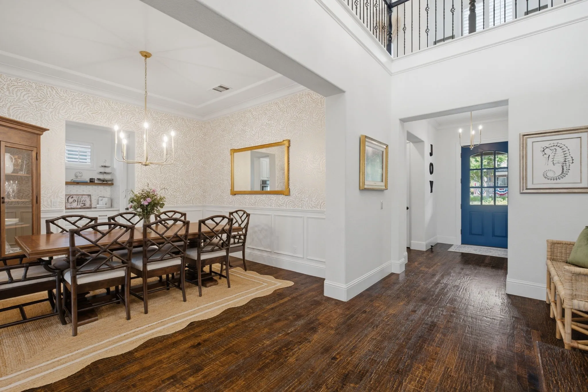 This formal dining room is located conveniently off the main entryway, showcasing sophisticated designer wallpaper and classic chair rail molding, while offering seamless, open-concept access to both the chef’s kitchen and the adjacent butler’s pantry for effortless entertaining.