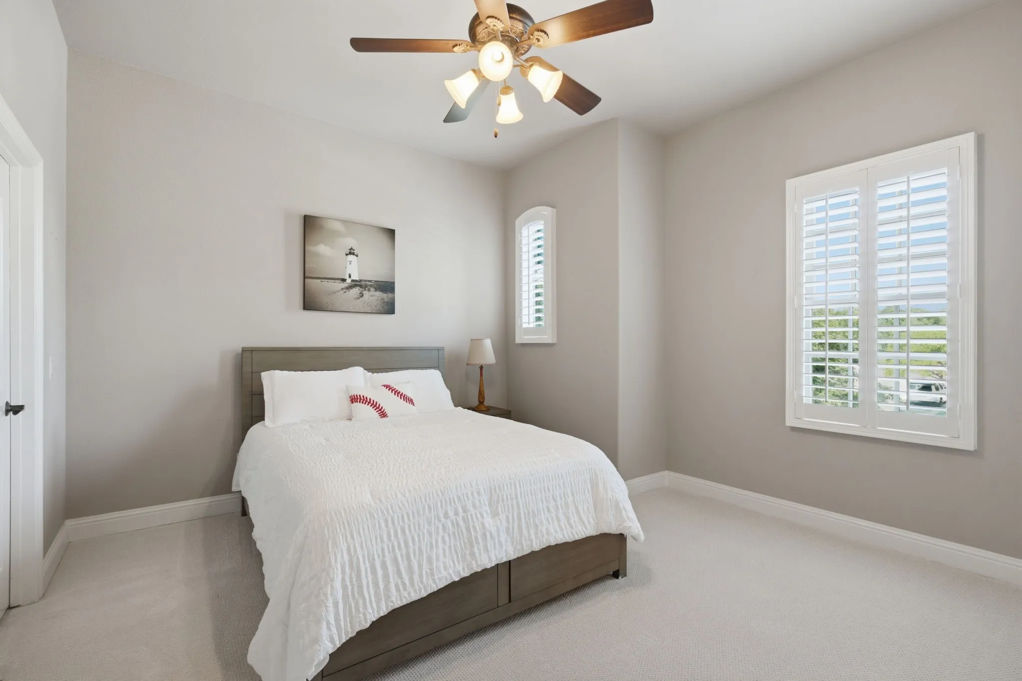 This spacious and light-filled upstairs secondary bedroom serves as a perfect retreat, featuring a generously sized walk-in closet for ample storage, elegant plantation shutters that provide both privacy and light control, and a modern ceiling fan to ensure year-round comfort.