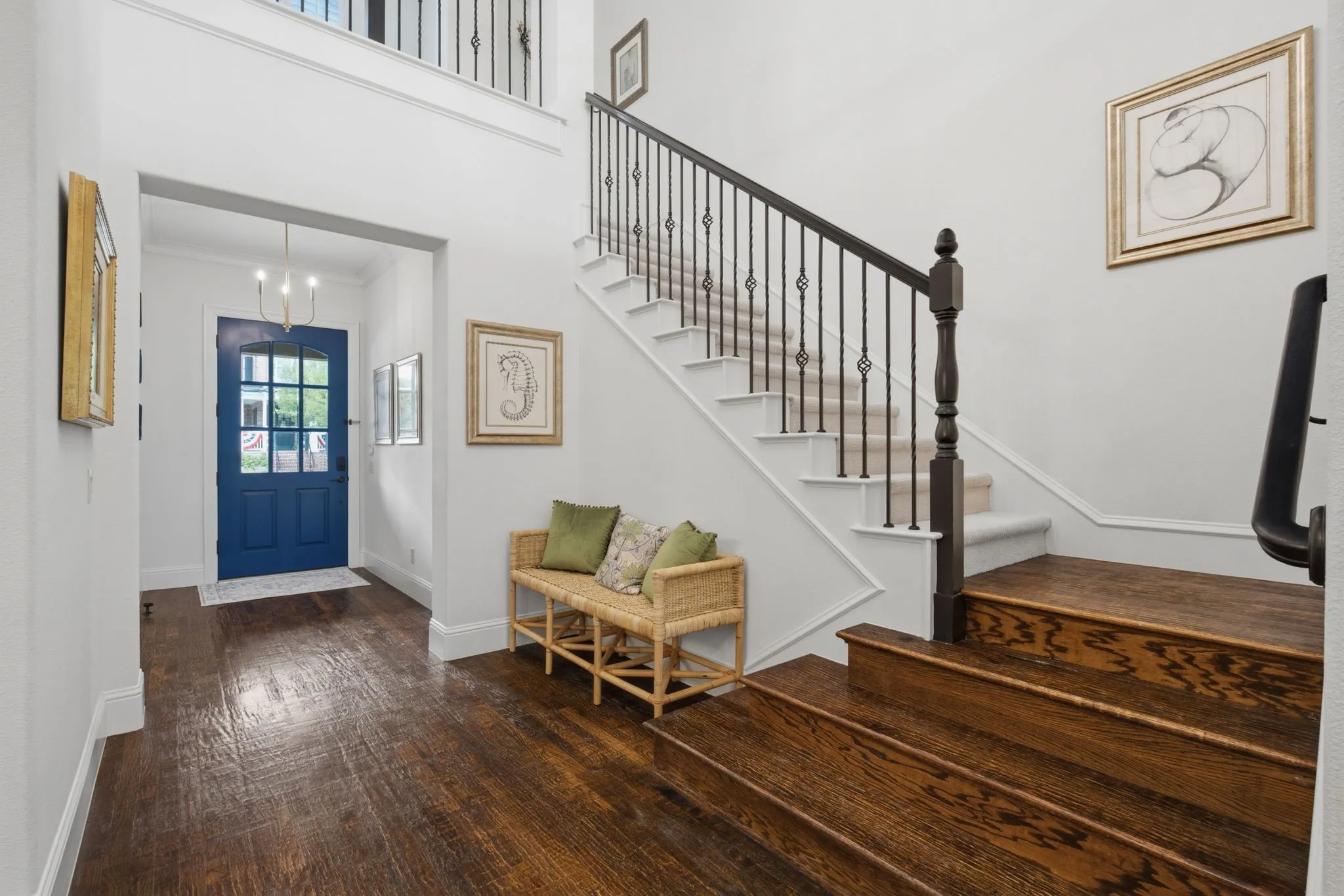 Exquisite Craftsman-style entrance foyer highlighting the warm, inviting hardwood stairs, complemented by a sophisticated custom wrought iron railing, all captured from an interior perspective looking directly toward the classic front door.