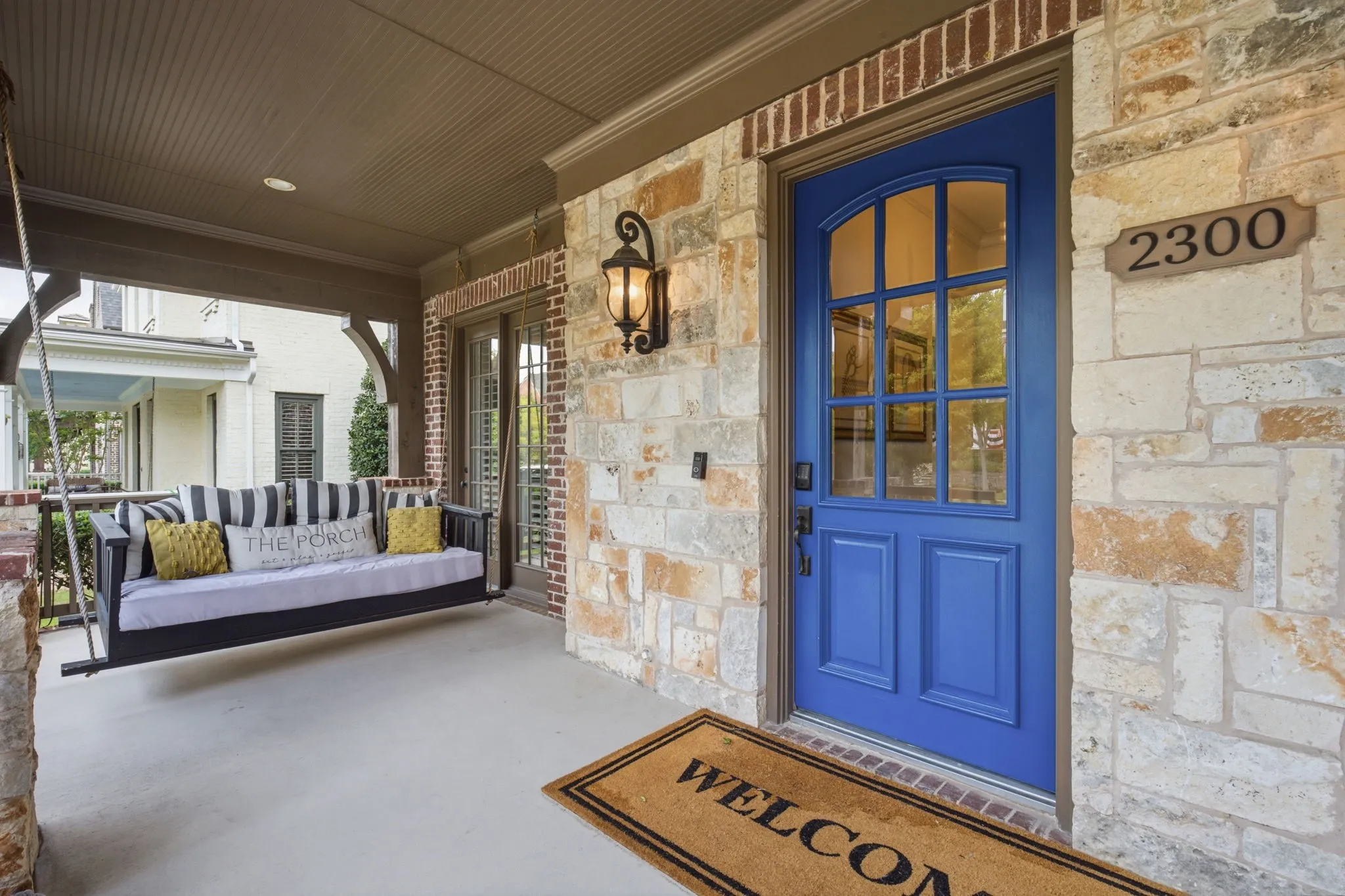This property boasts an incredibly expansive and inviting covered entry porch that serves as the perfect outdoor retreat, highlighted by a charming and relaxing daybed swing that offers a peaceful spot to unwind while enjoying the fresh air.