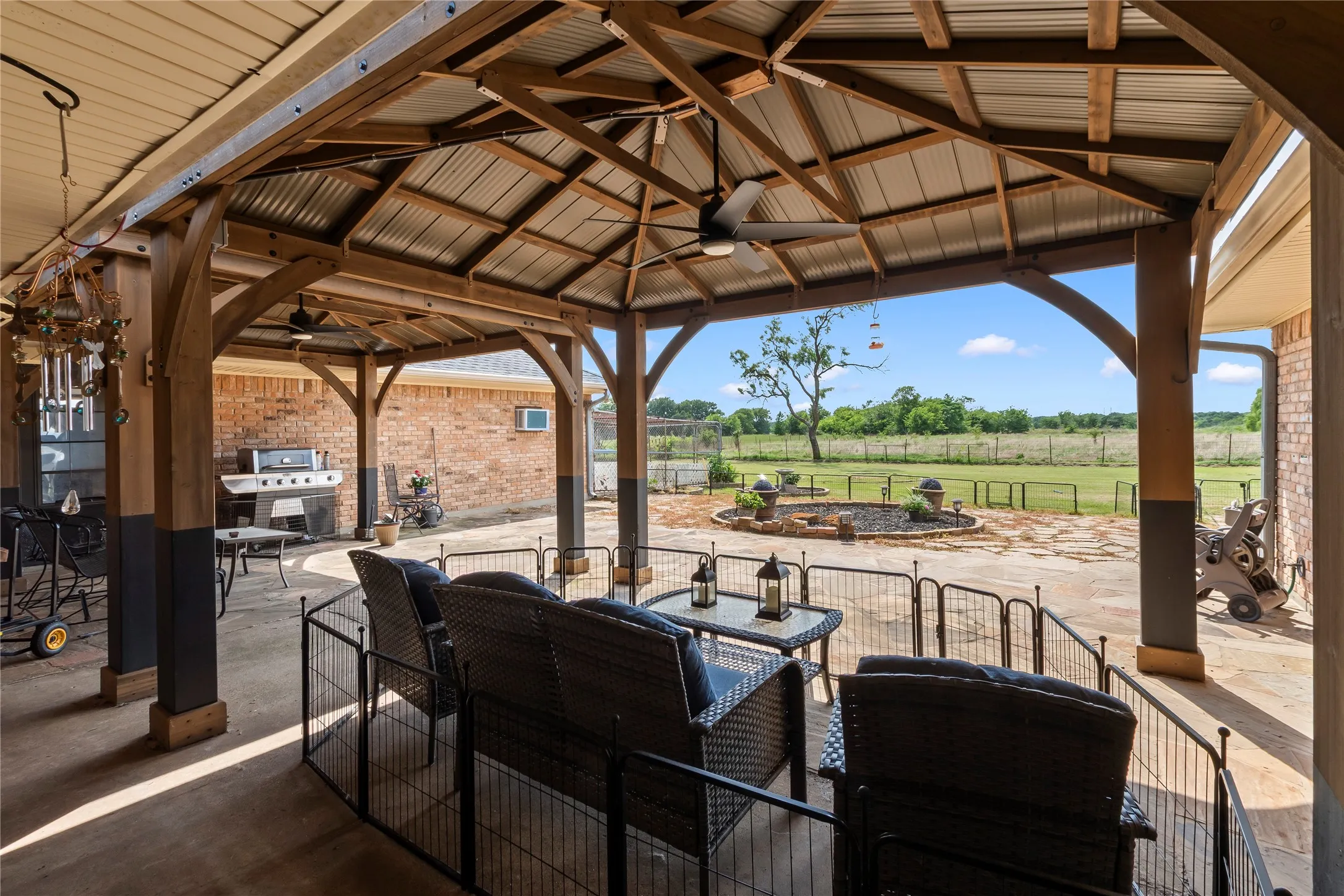 Expansive covered patio featuring a corrugated metal roof, exposed wood beams, and ceiling fans