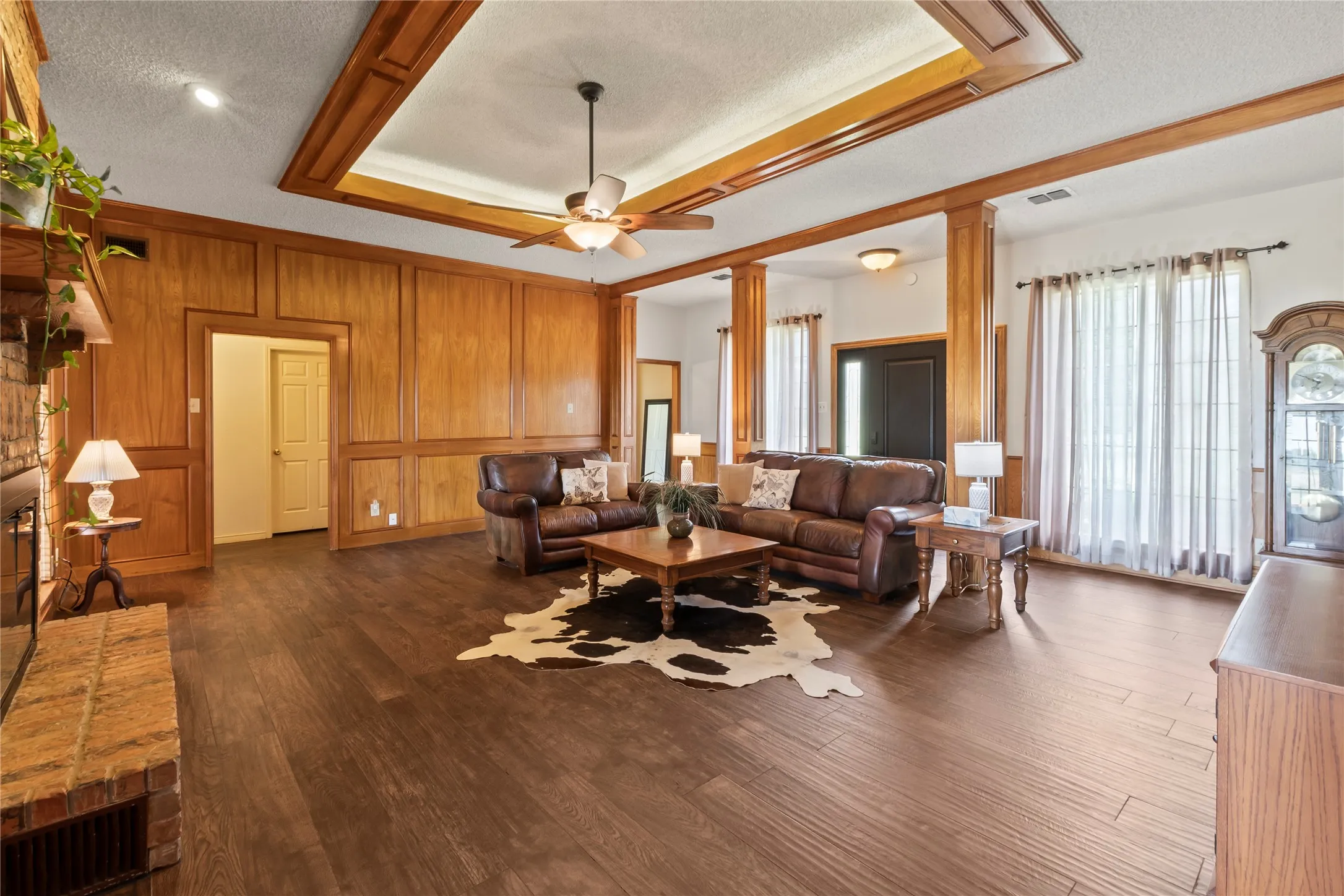 Living area featuring wood-finish flooring, paneled wall detailing, and a coffered ceiling with a ceiling fan