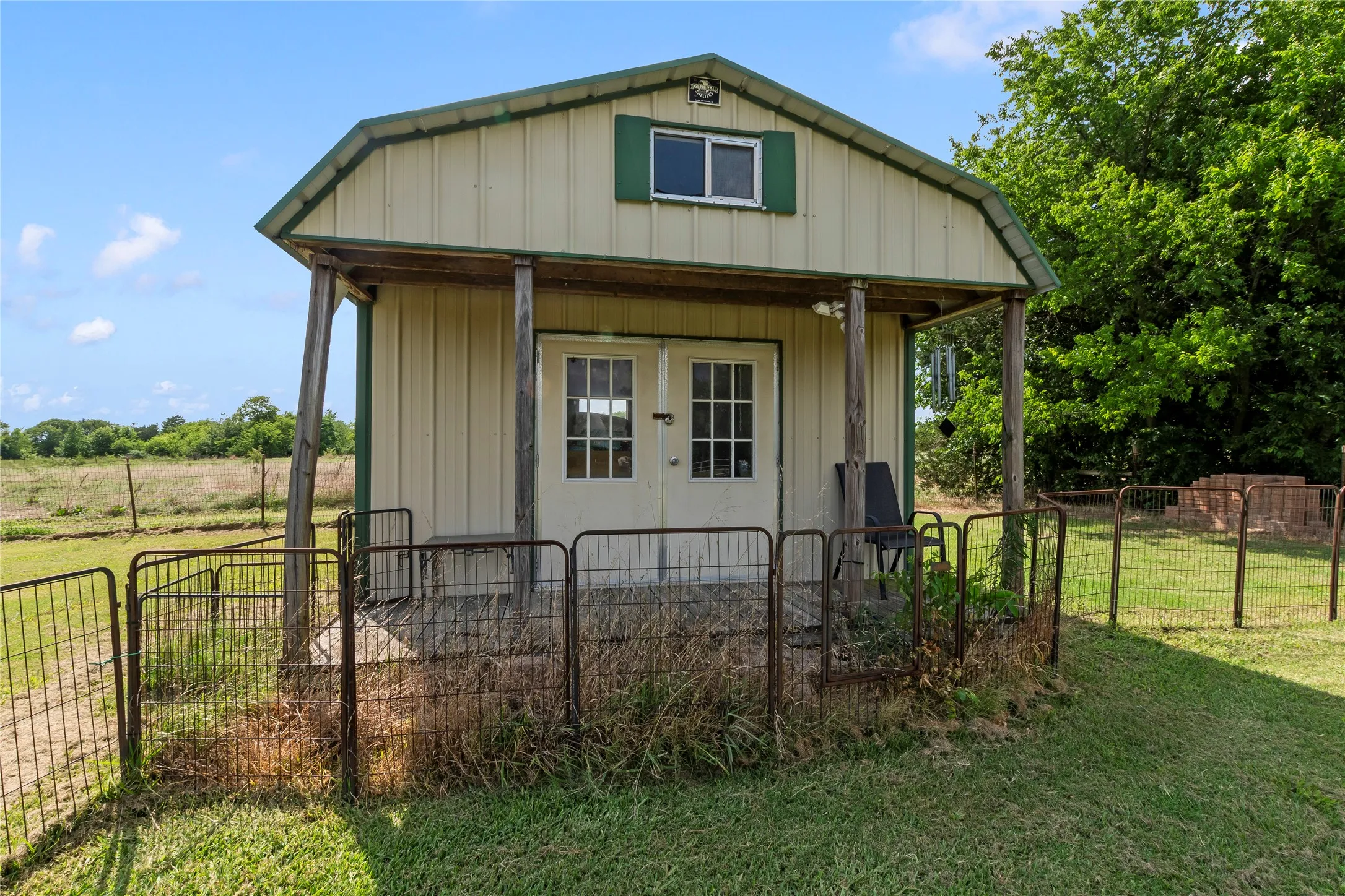 Metal-sided barn structure featuring a gambrel roof and green trim