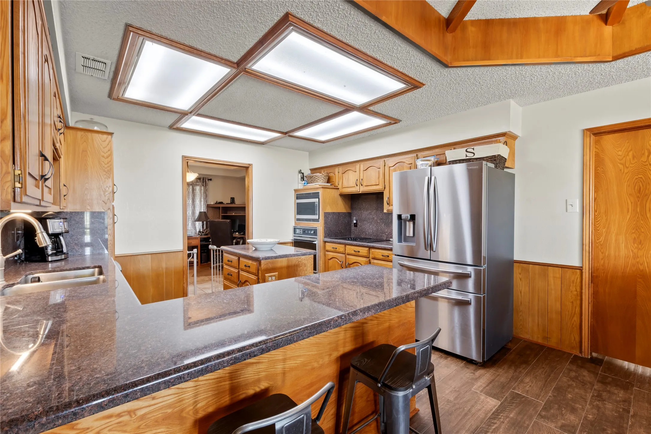 Kitchen featuring wood-finish cabinetry, dark speckled countertops, and stainless steel appliances