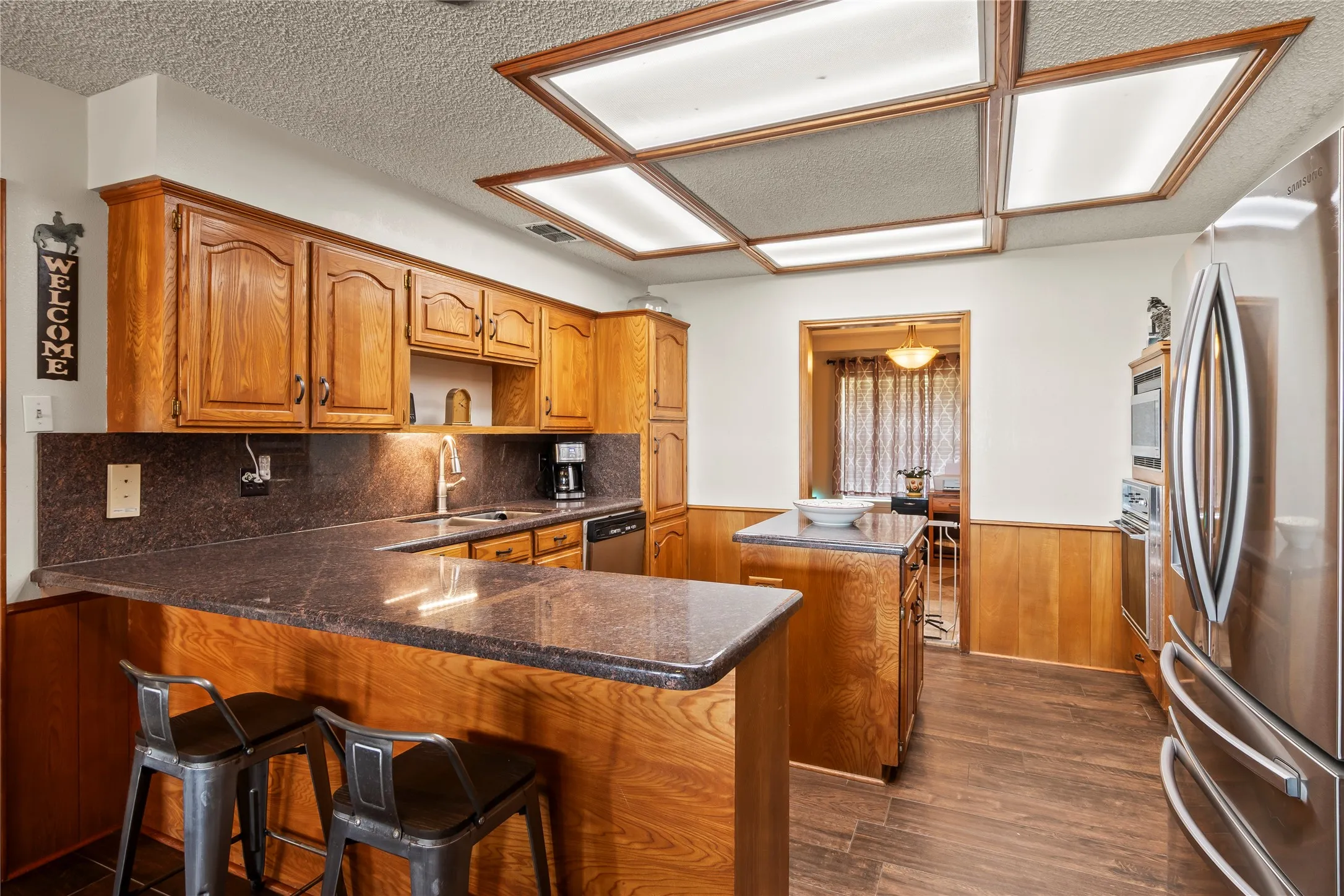 Kitchen featuring wood-finish cabinetry, dark countertops, and stainless steel appliances
