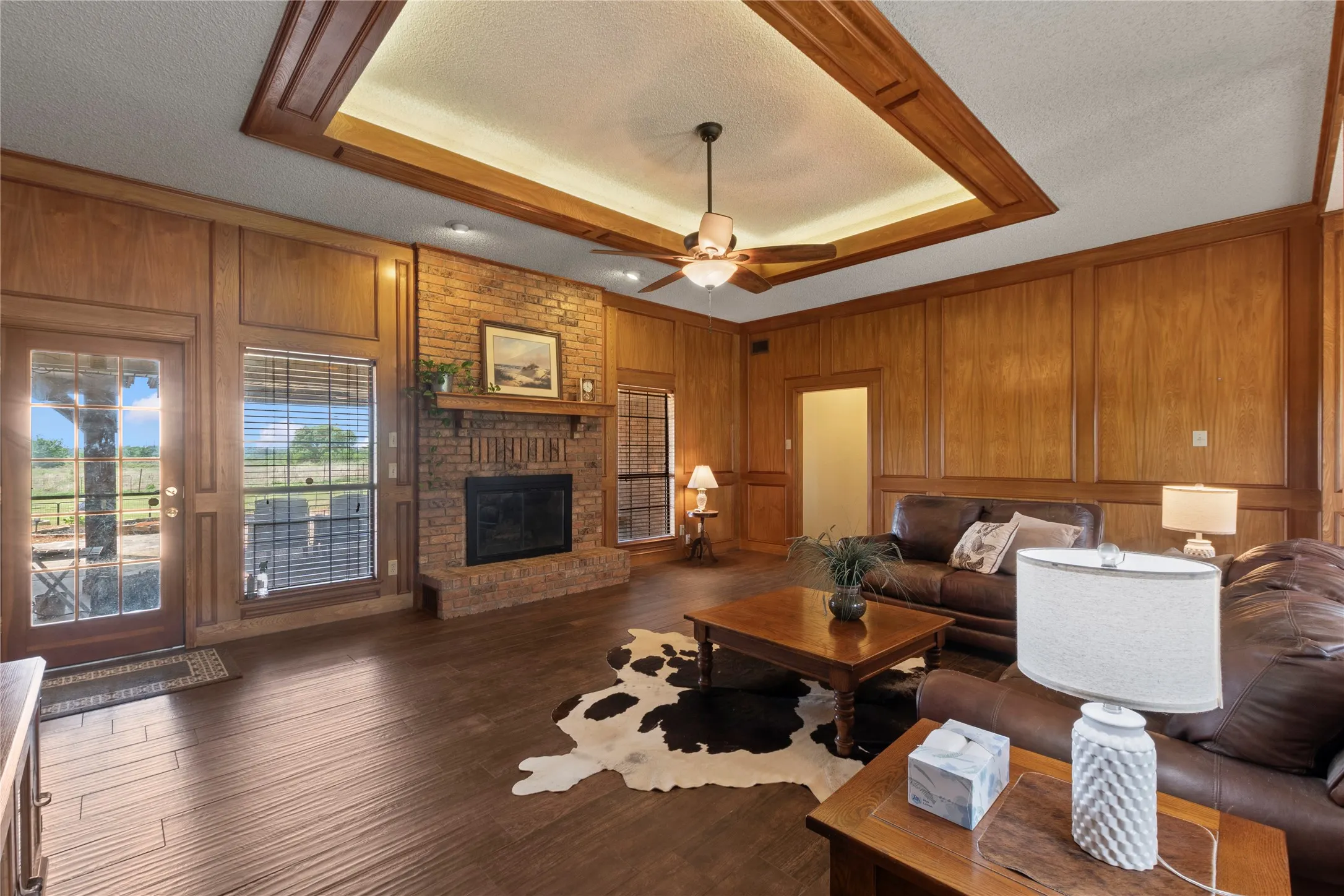 Spacious living area featuring wood-finish flooring, wood paneling, and a brick fireplace
