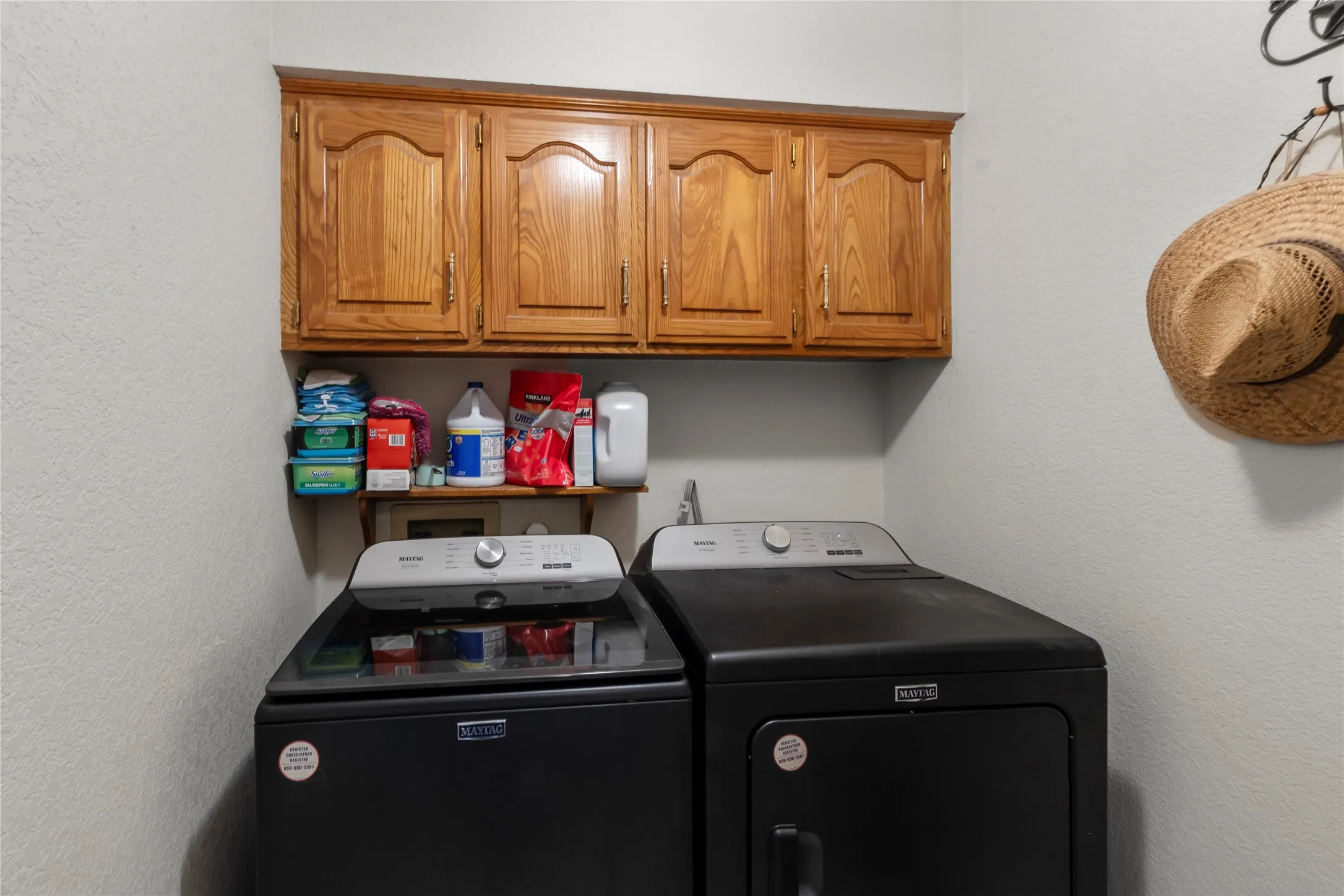 Dedicated laundry area featuring wood-finish cabinetry, a built-in shelf, and light-toned wall finishes