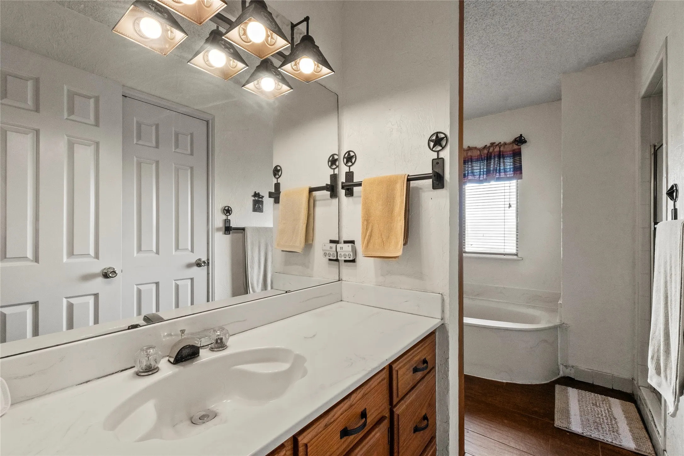 Vanity area featuring a single basin sink, white countertop, and wood-finish cabinetry