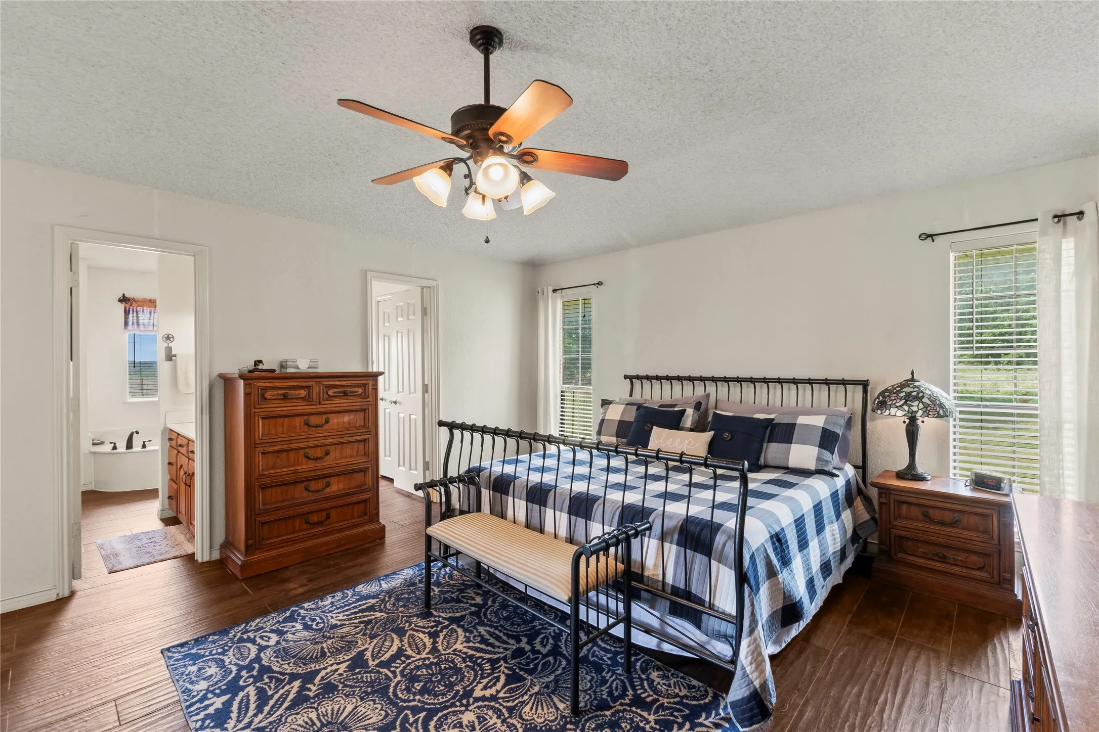 Spacious room featuring wood-finish flooring, a ceiling fan with integrated lighting, and white walls