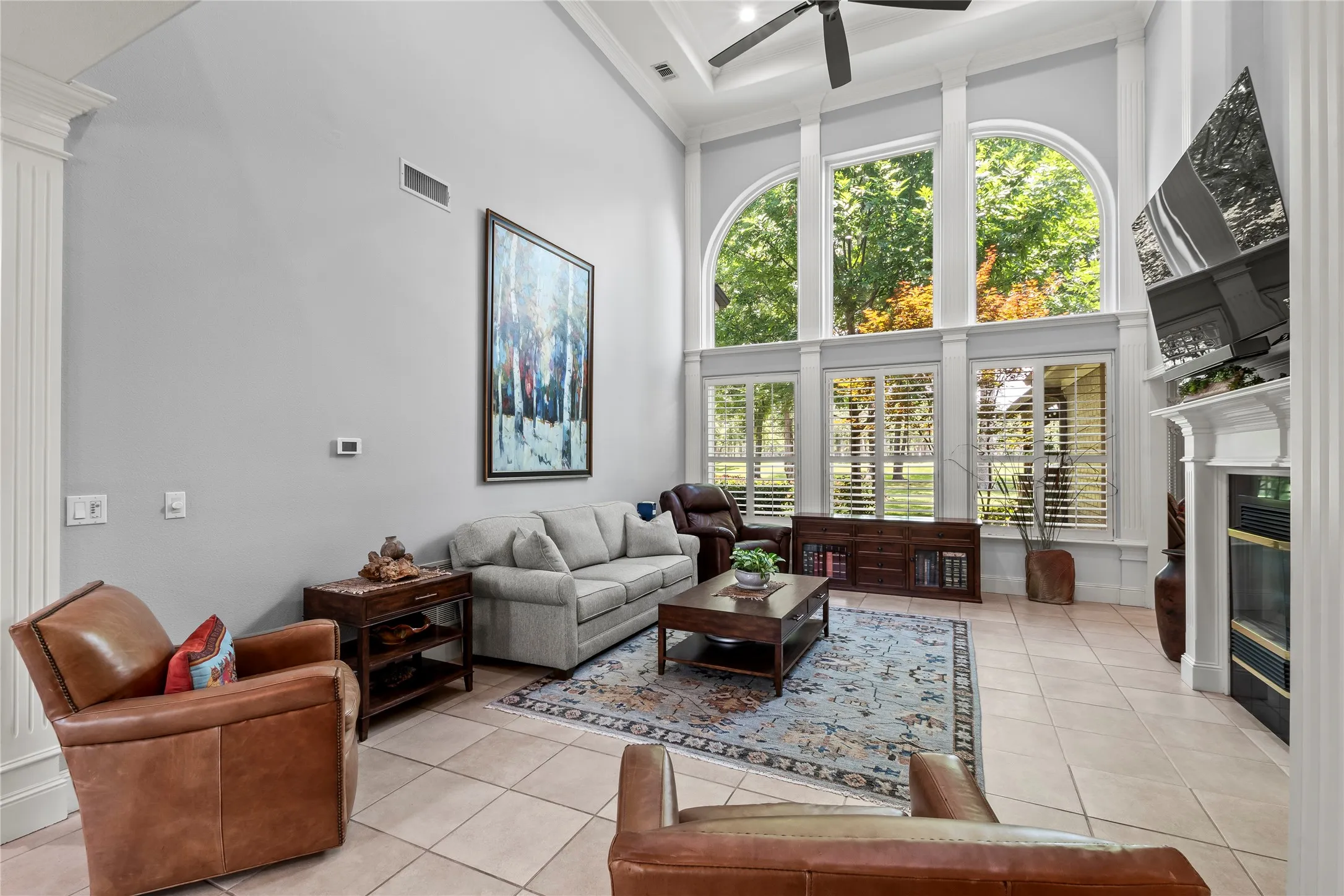  Living room with gas fireplace and large windows with natural light and plantation shutters.