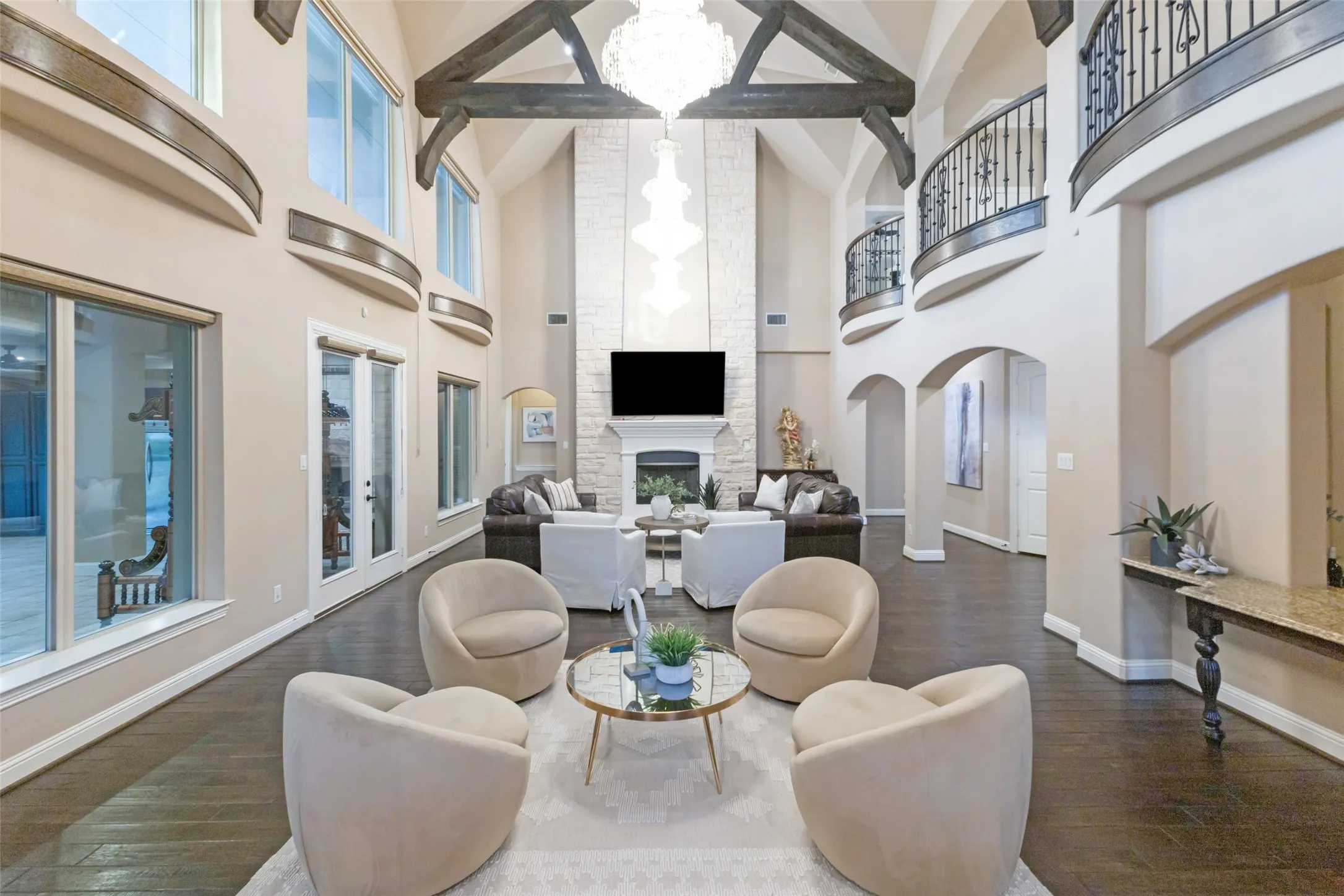 Great room with 3 stunning Swarovski crystal chandeliers, wood beams, hardwood flooring and wrought iron balcony overlooks from the second floor.