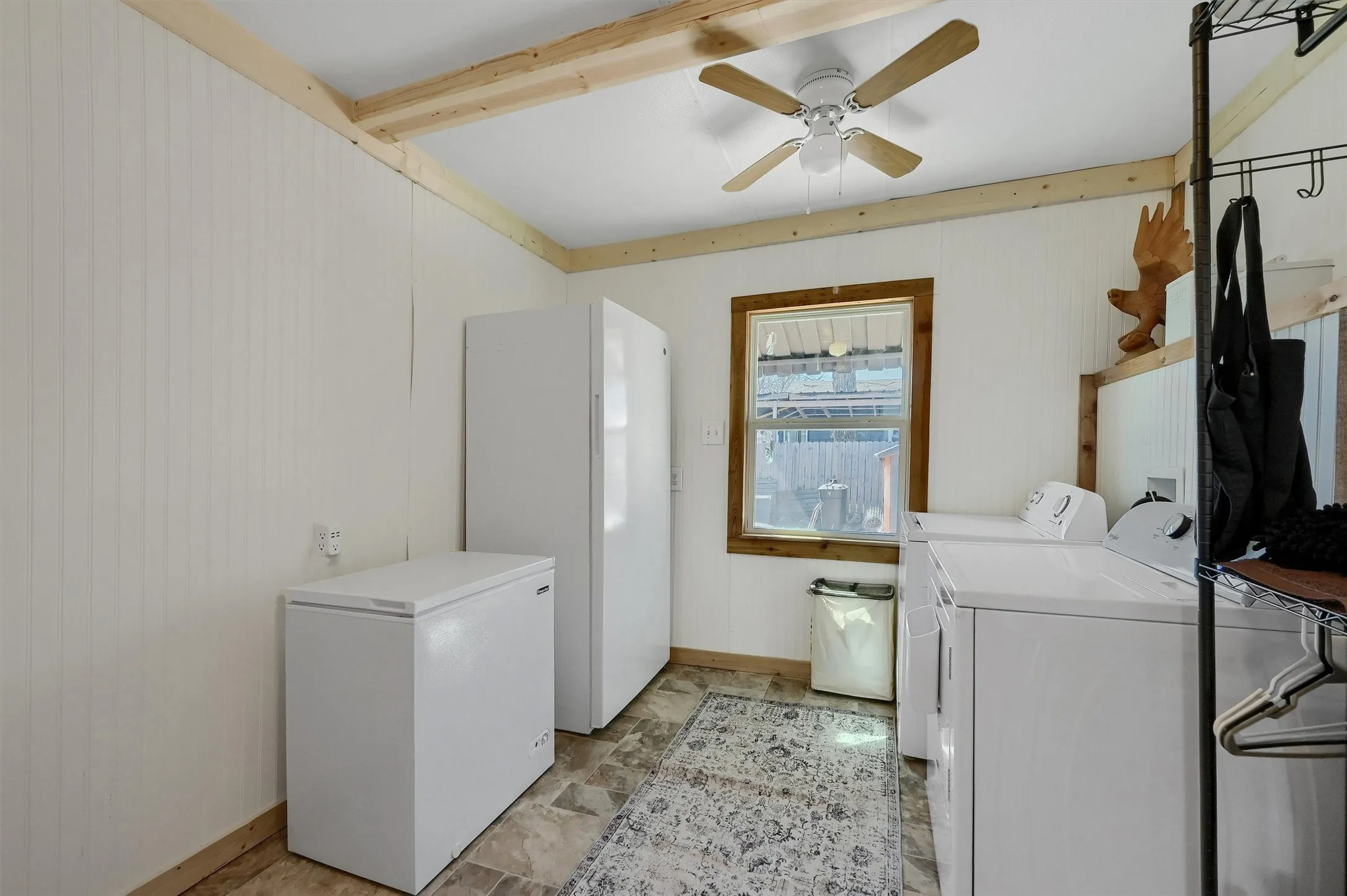 Utility area featuring wood-finish ceiling beams, beadboard wall paneling, and a ceiling fan