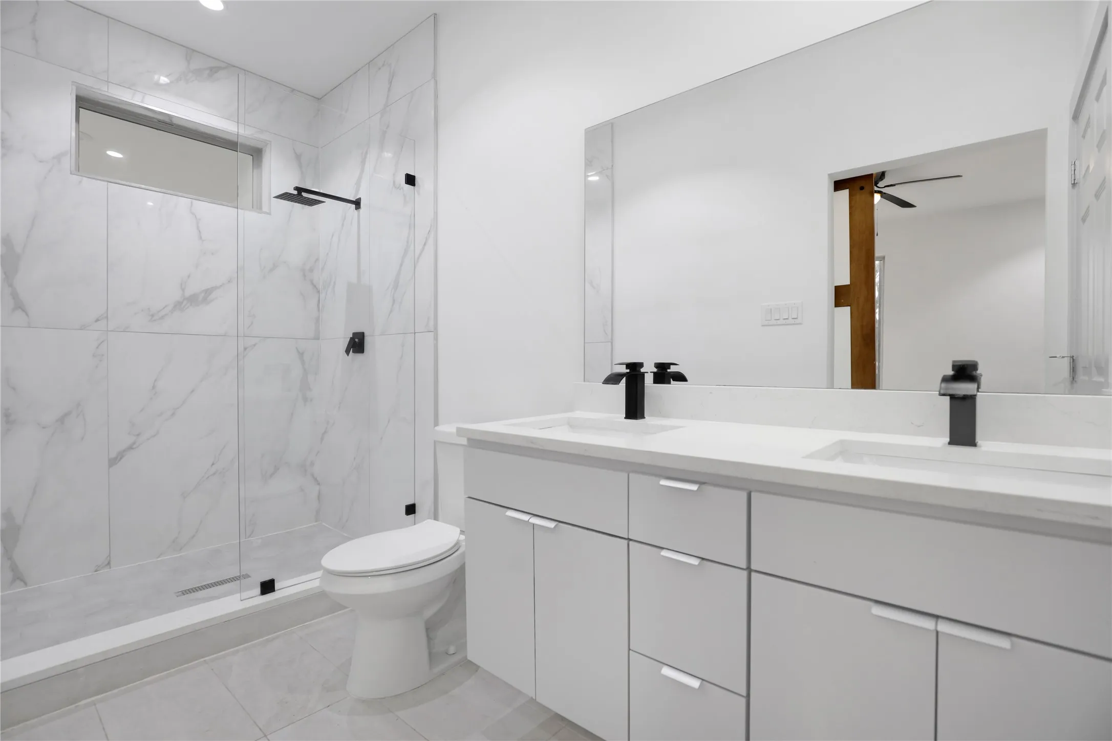 Bathroom featuring a dual vanity with white cabinetry, integrated sinks, and matte black fixtures