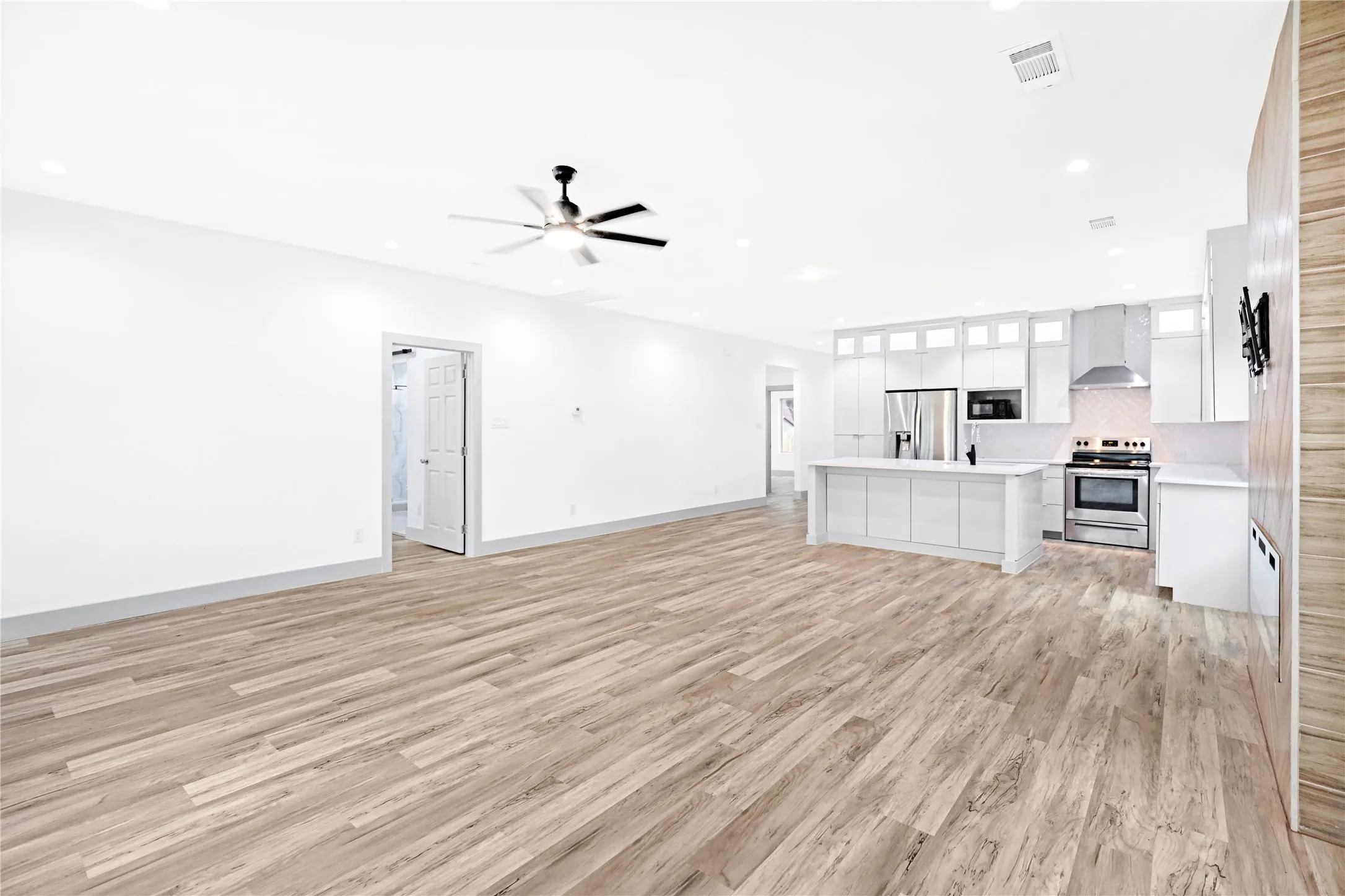 Open-concept living space featuring wood-finish flooring, recessed lighting, and a ceiling fan