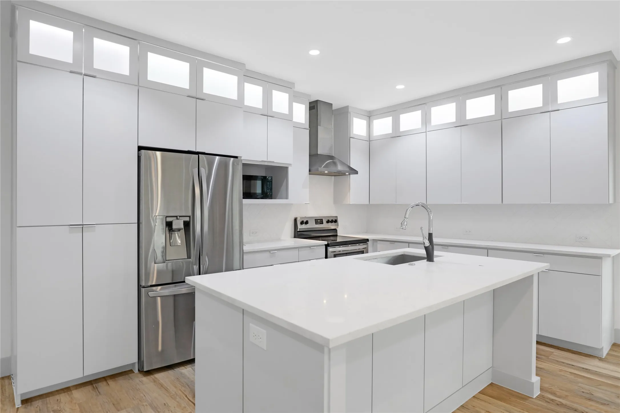 Modern kitchen featuring light wood-finish flooring and extensive white cabinetry