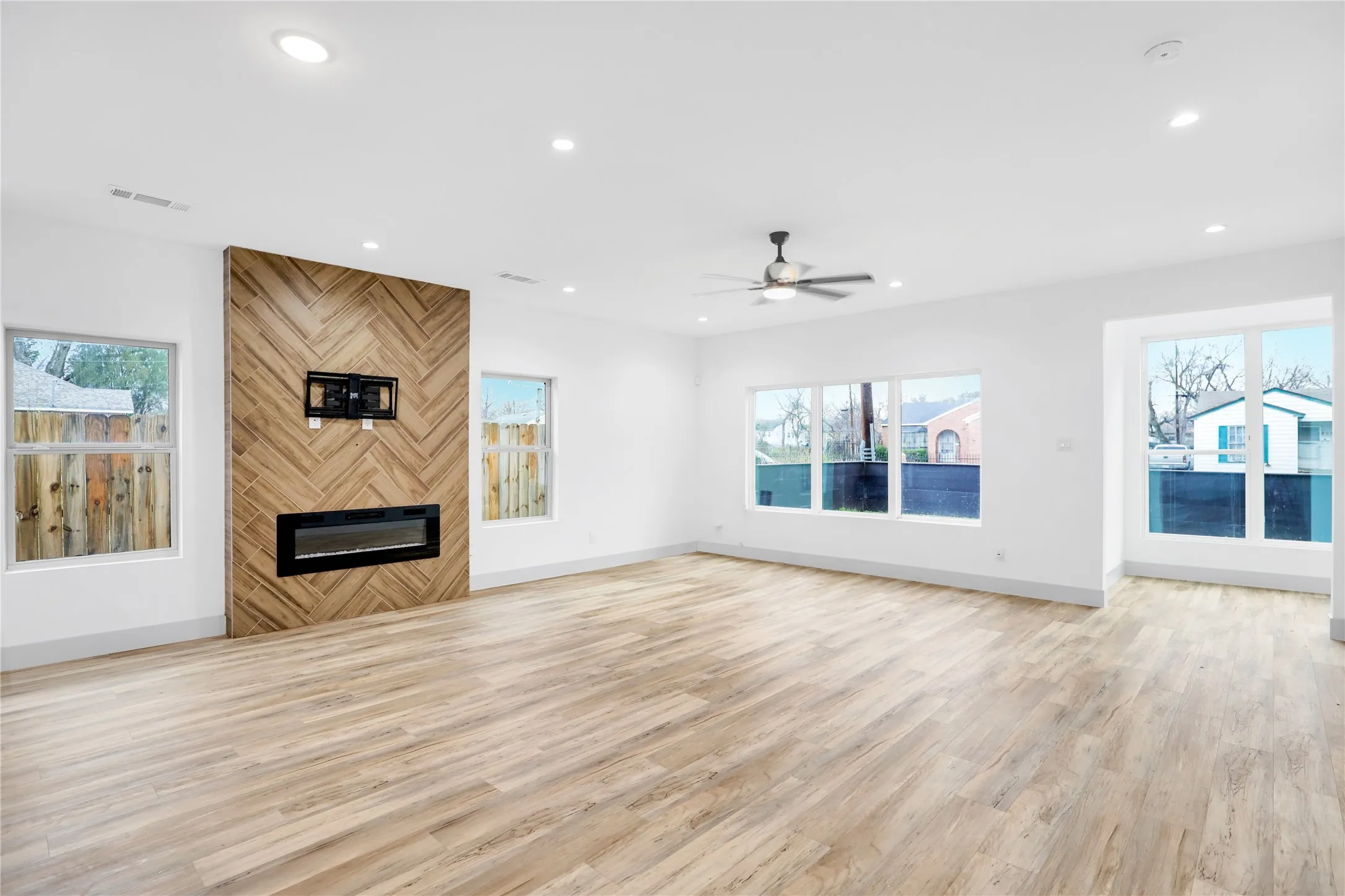 Spacious living area featuring light wood-finish flooring, recessed lighting, and a modern ceiling fan