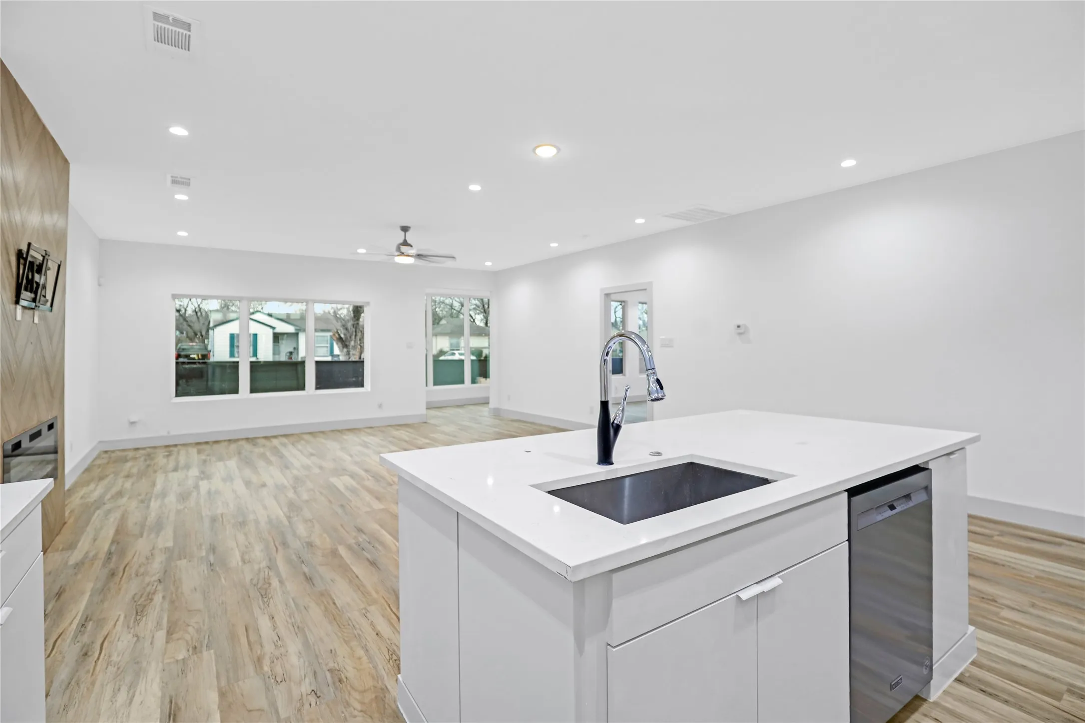 Kitchen island featuring a stainless steel undermount sink with a matte black faucet, integrated dishwasher, and white countertop