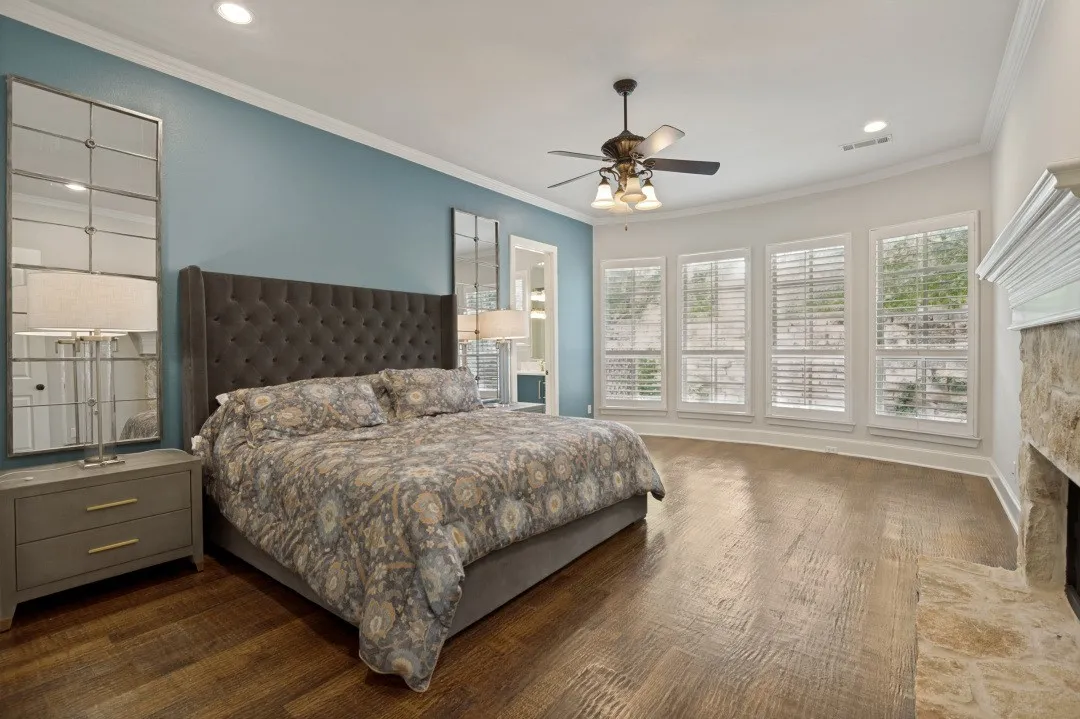 Spacious room featuring wood-finish flooring, a stone fireplace, and a vaulted ceiling with a ceiling fan