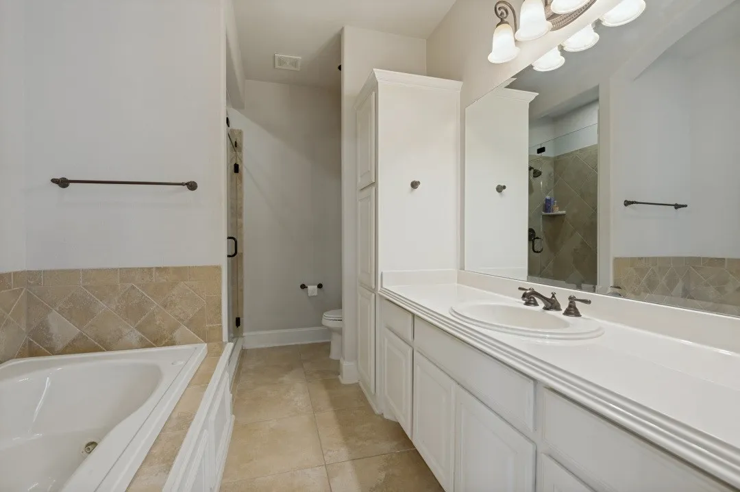 Bathroom featuring an expansive vanity with an integrated sink, white cabinetry, and a large mirror