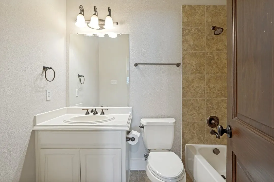 Bathroom featuring a white vanity with an undermount sink, a coordinating white countertop, and a dark bronze faucet