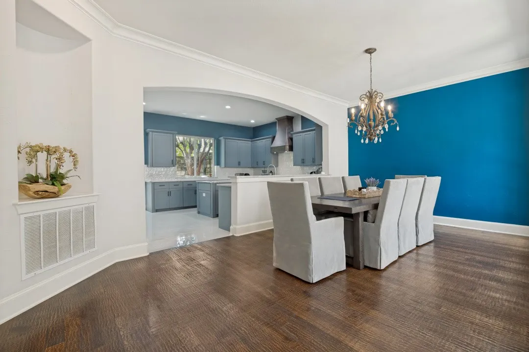 Dining area featuring wood-finish flooring, a decorative chandelier, and an accent wall