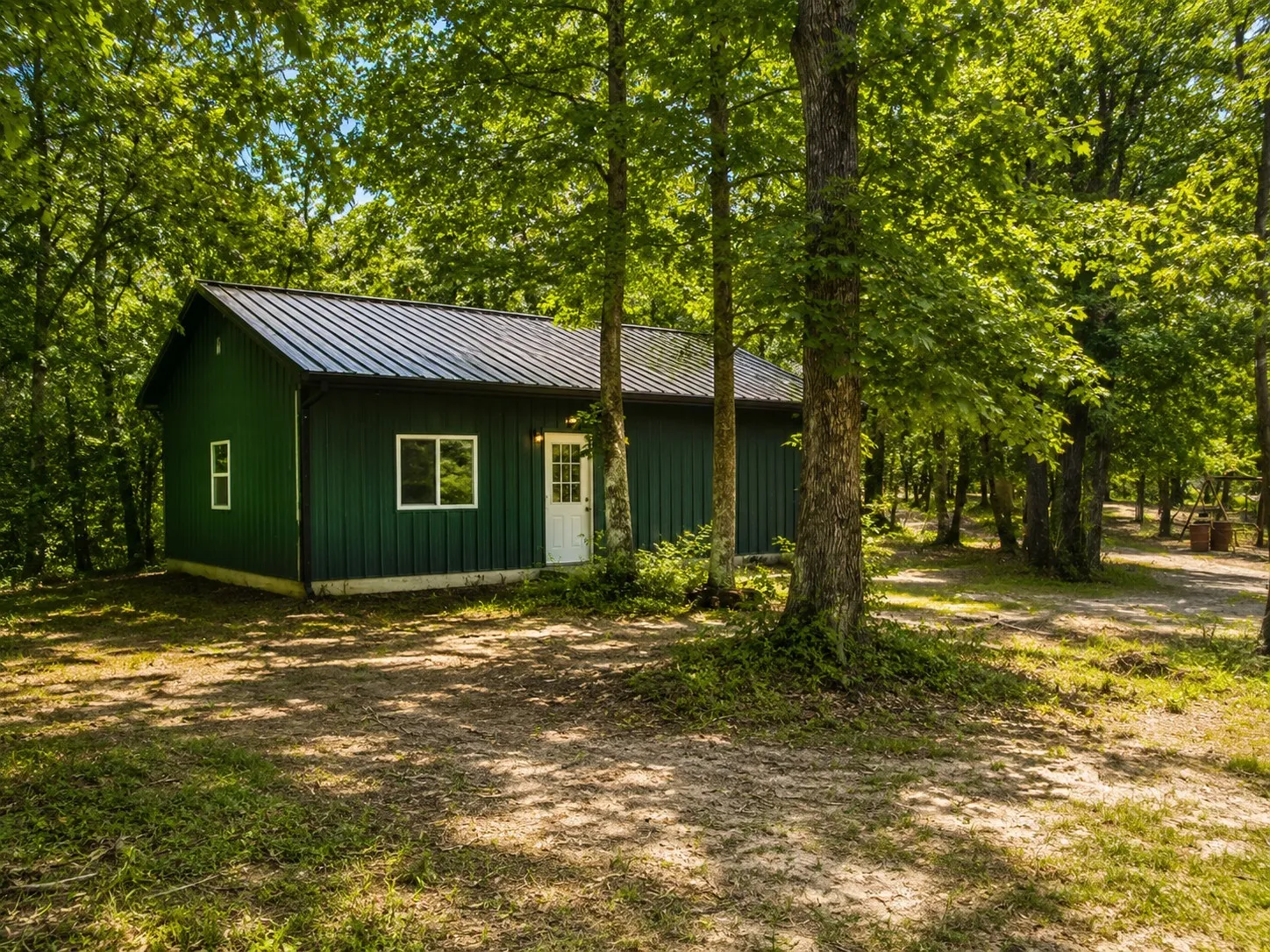 Standalone structure featuring dark green vertical siding and a black metal roof