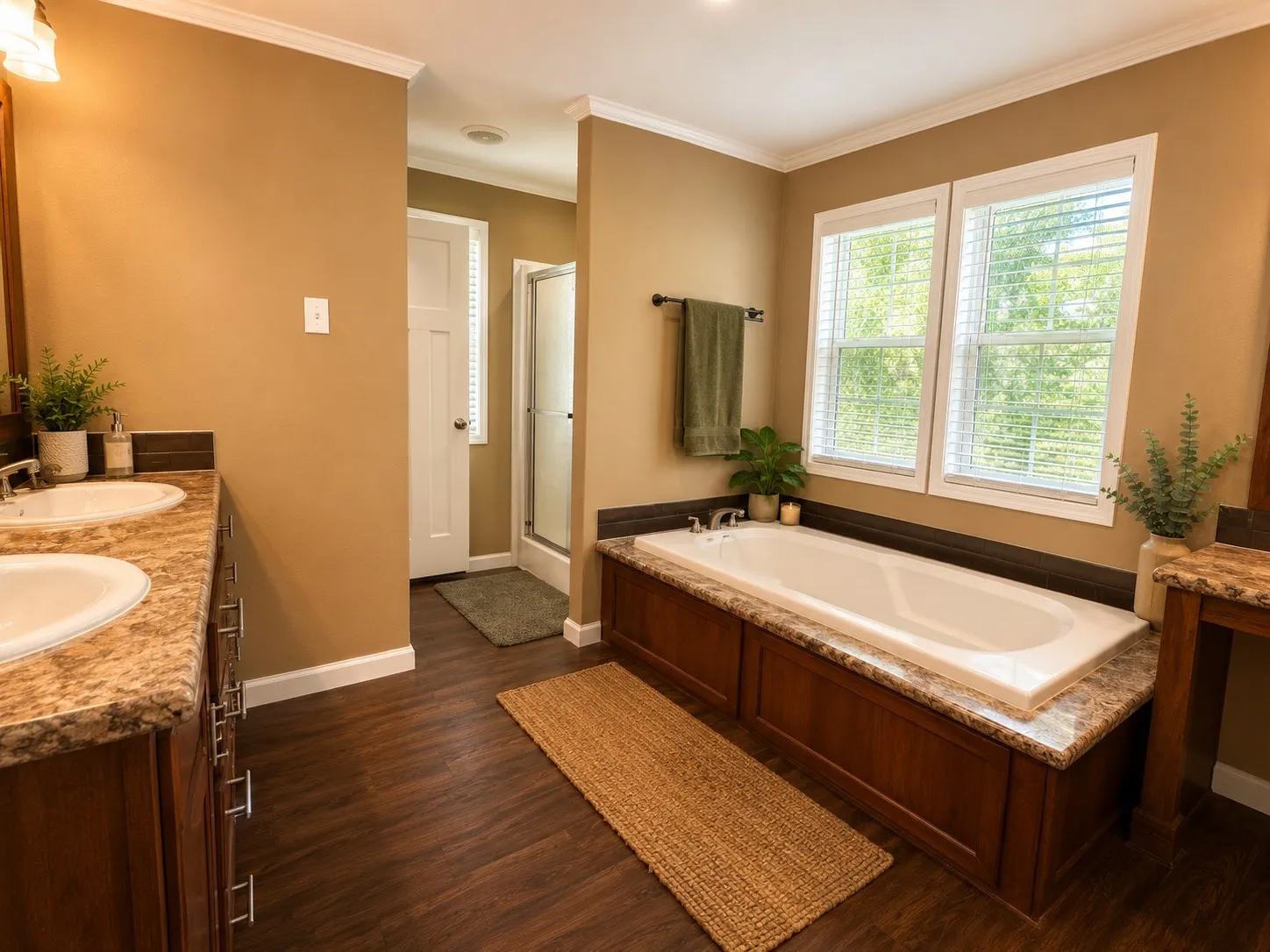 Bathroom featuring a built-in tub, dual sink vanity with stone-finish countertops, wood-finish flooring, and crown molding