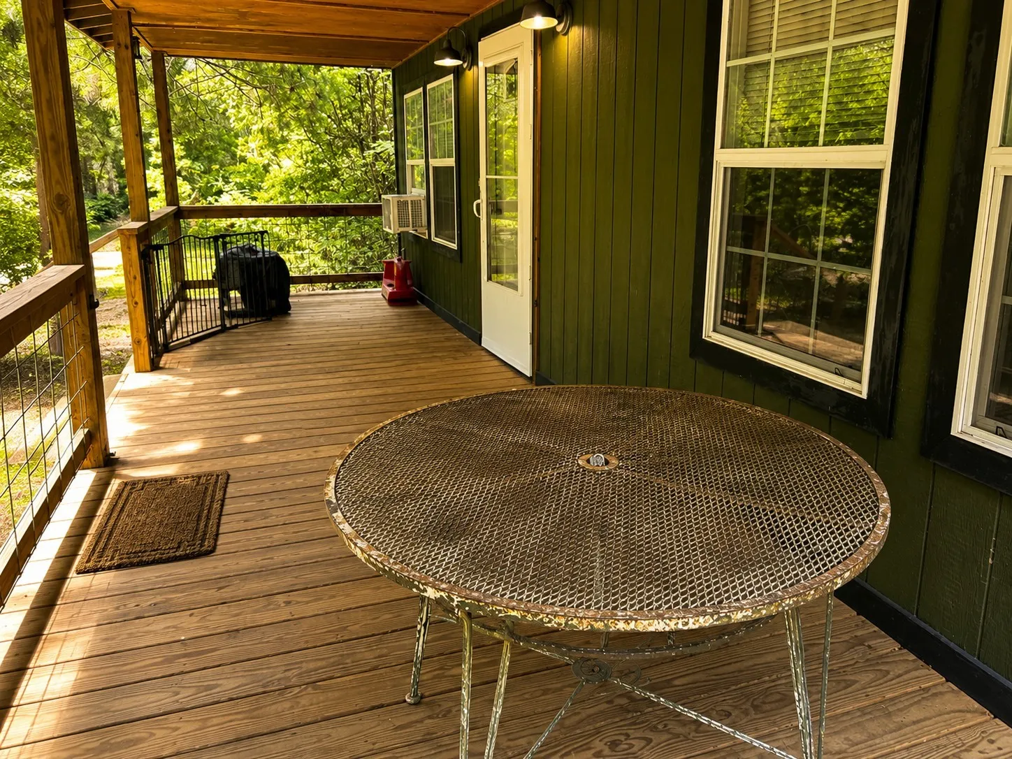 Expansive covered deck featuring natural wood flooring and a sturdy wood railing with metal infill