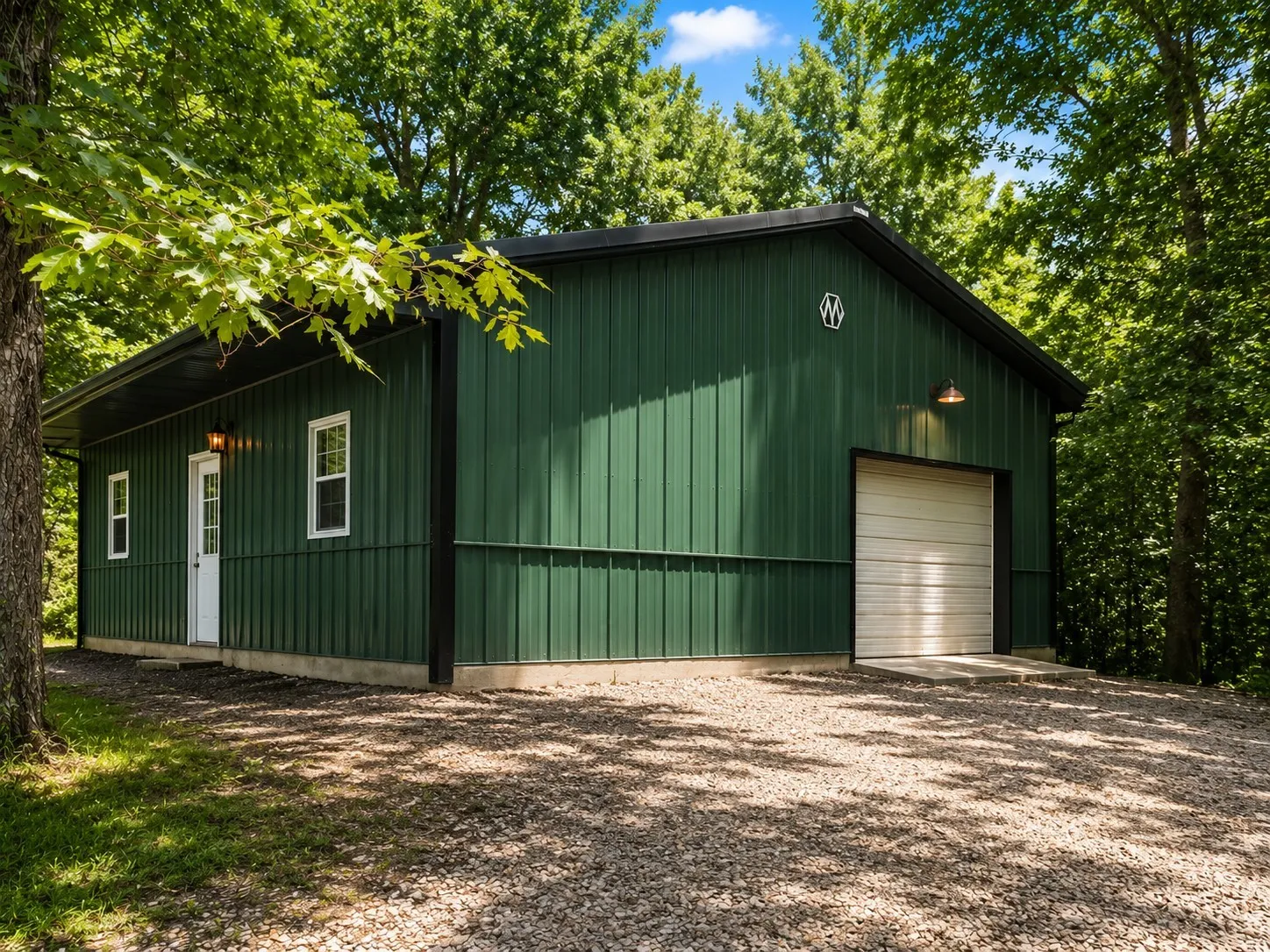 Green metal siding building with a black roofline and a white garage door