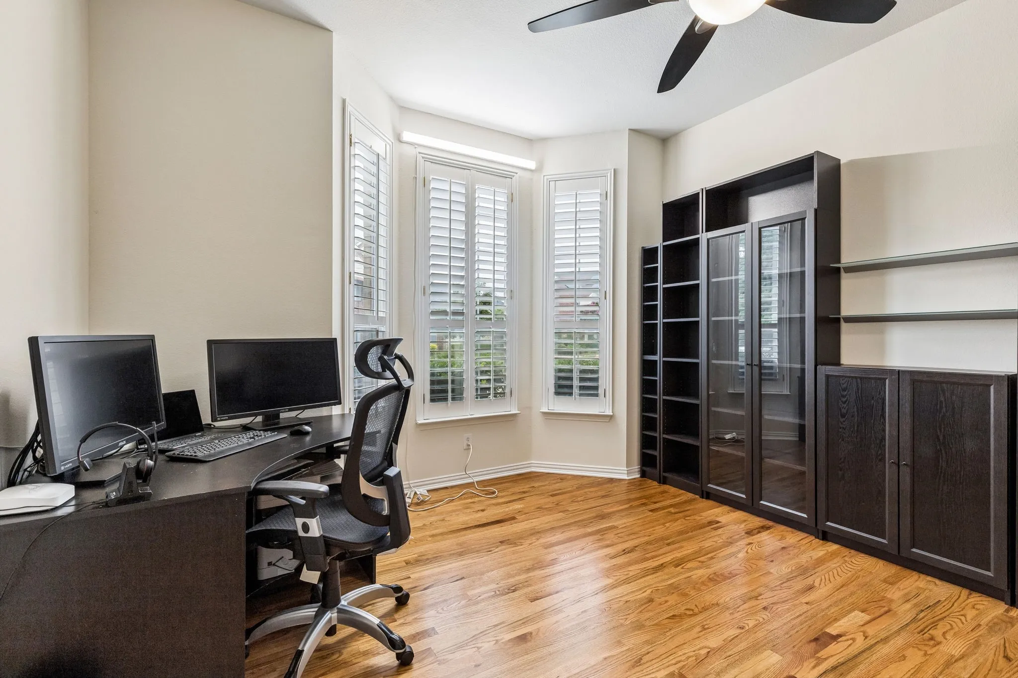 A large office with double doors in the front of the home. The window offers a pleasant view of the front yard, providing a calming backdrop for working.