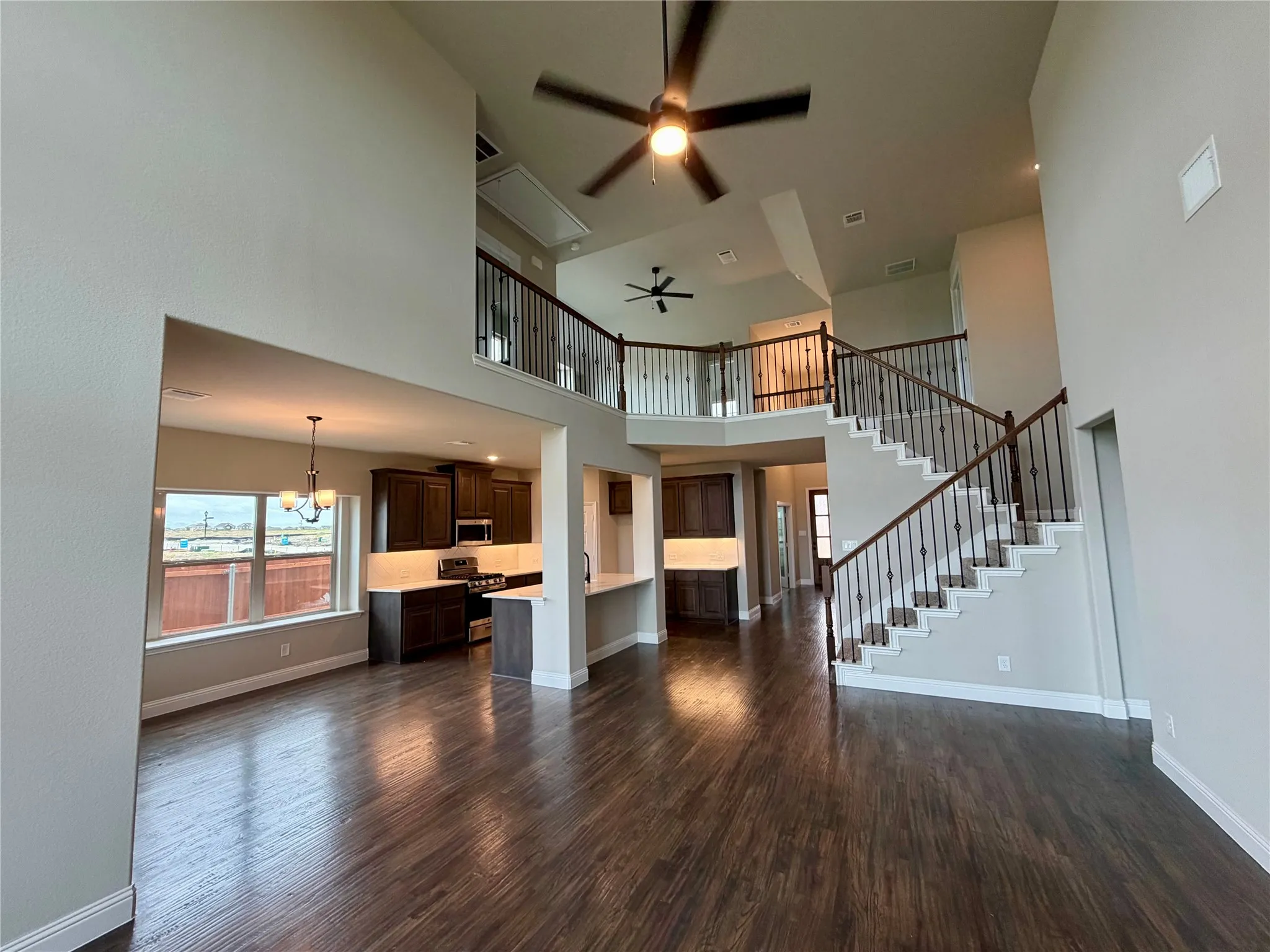 Great room with impressive cathedral ceiling, REAL hardwoods, and wrought iron spindles on staircase