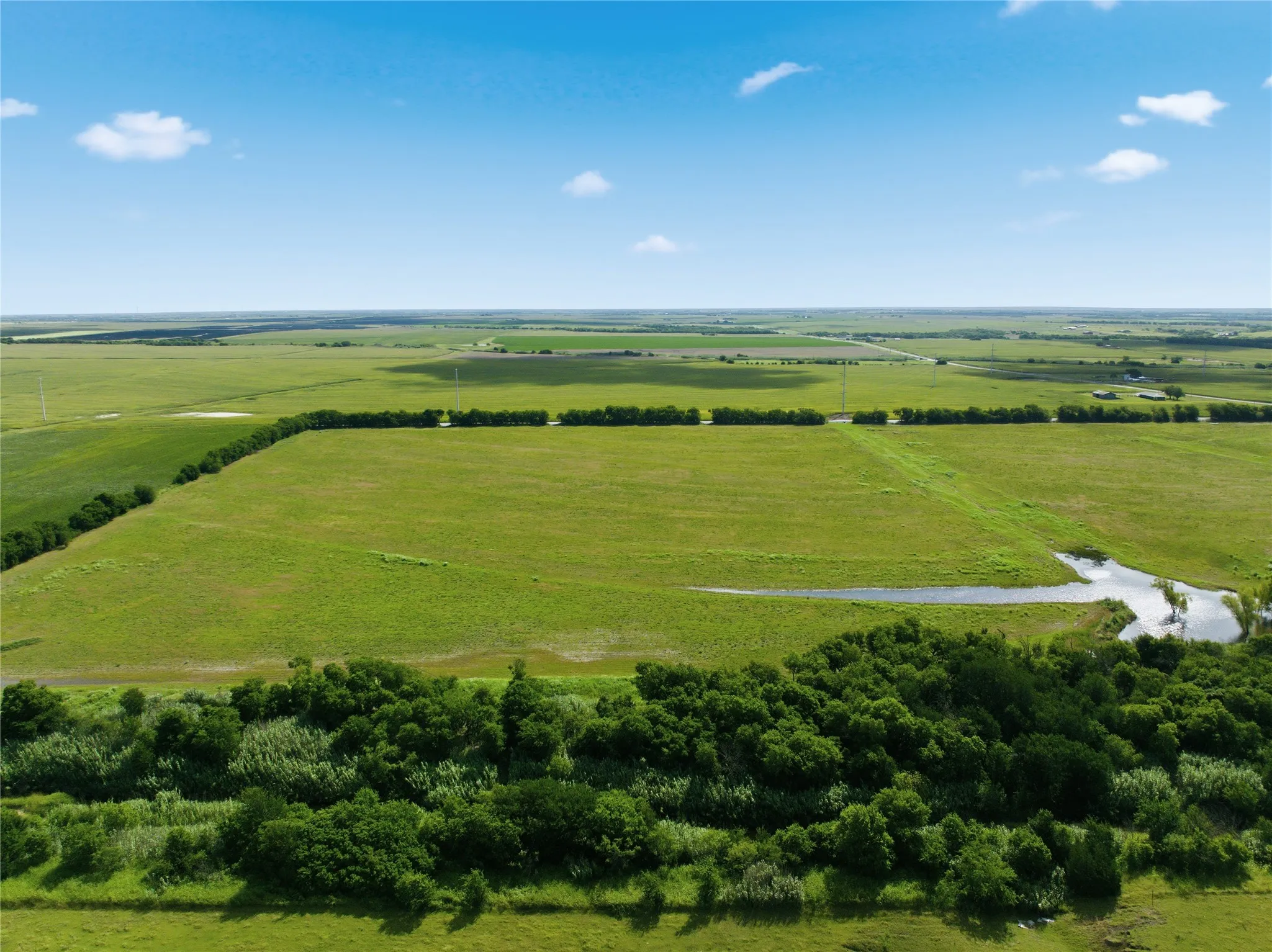 Expansive green fields featuring natural water features and mature tree lines