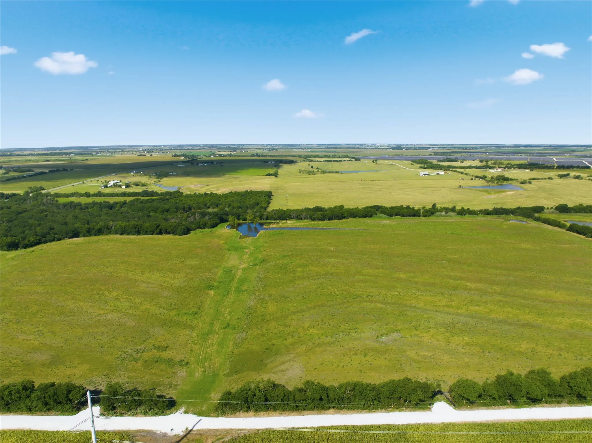 Expansive open acreage featuring a large pond and tree lines