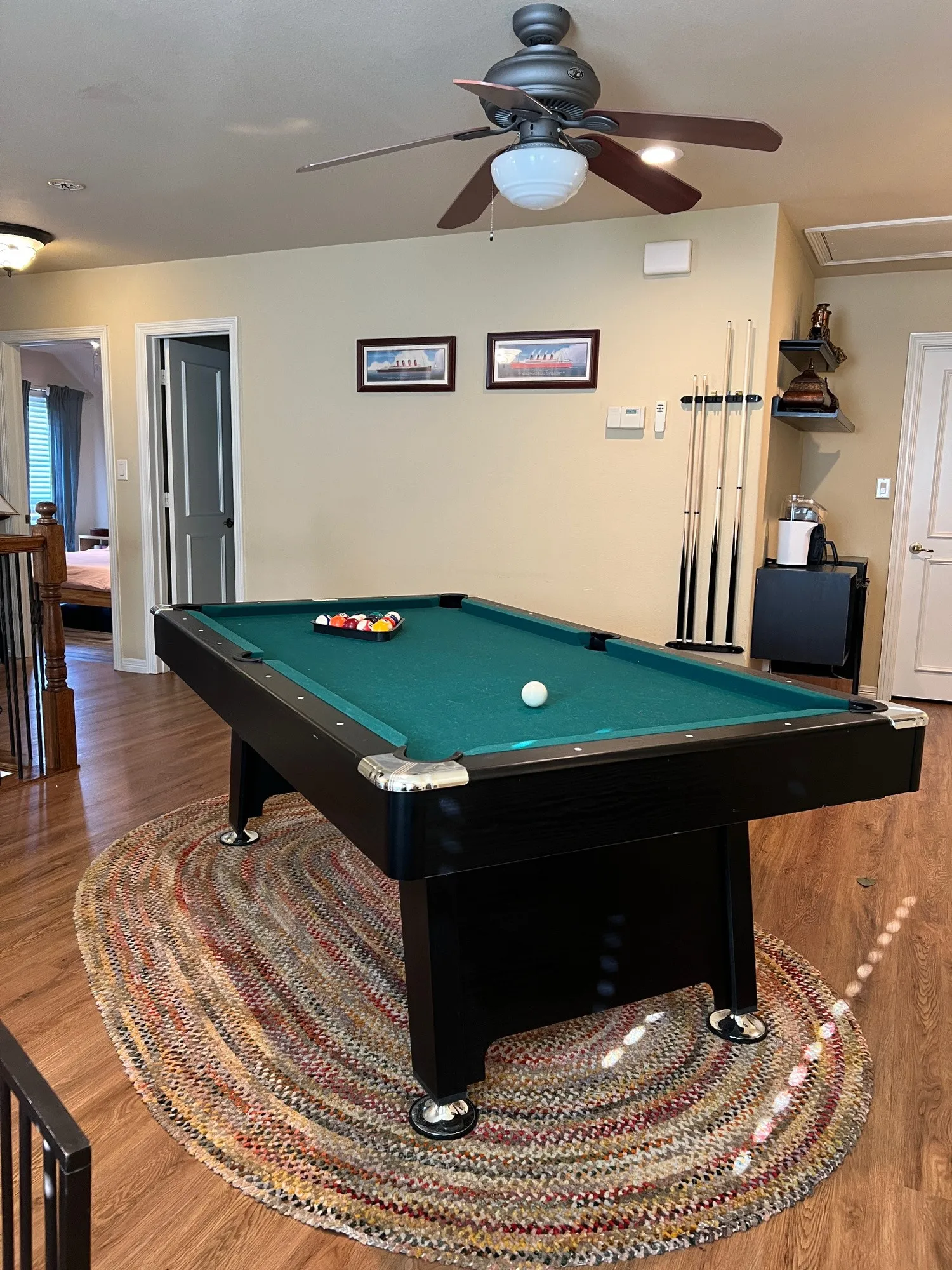 Recreational area featuring wood-finish flooring, light-toned walls, and a ceiling fan with integrated lighting