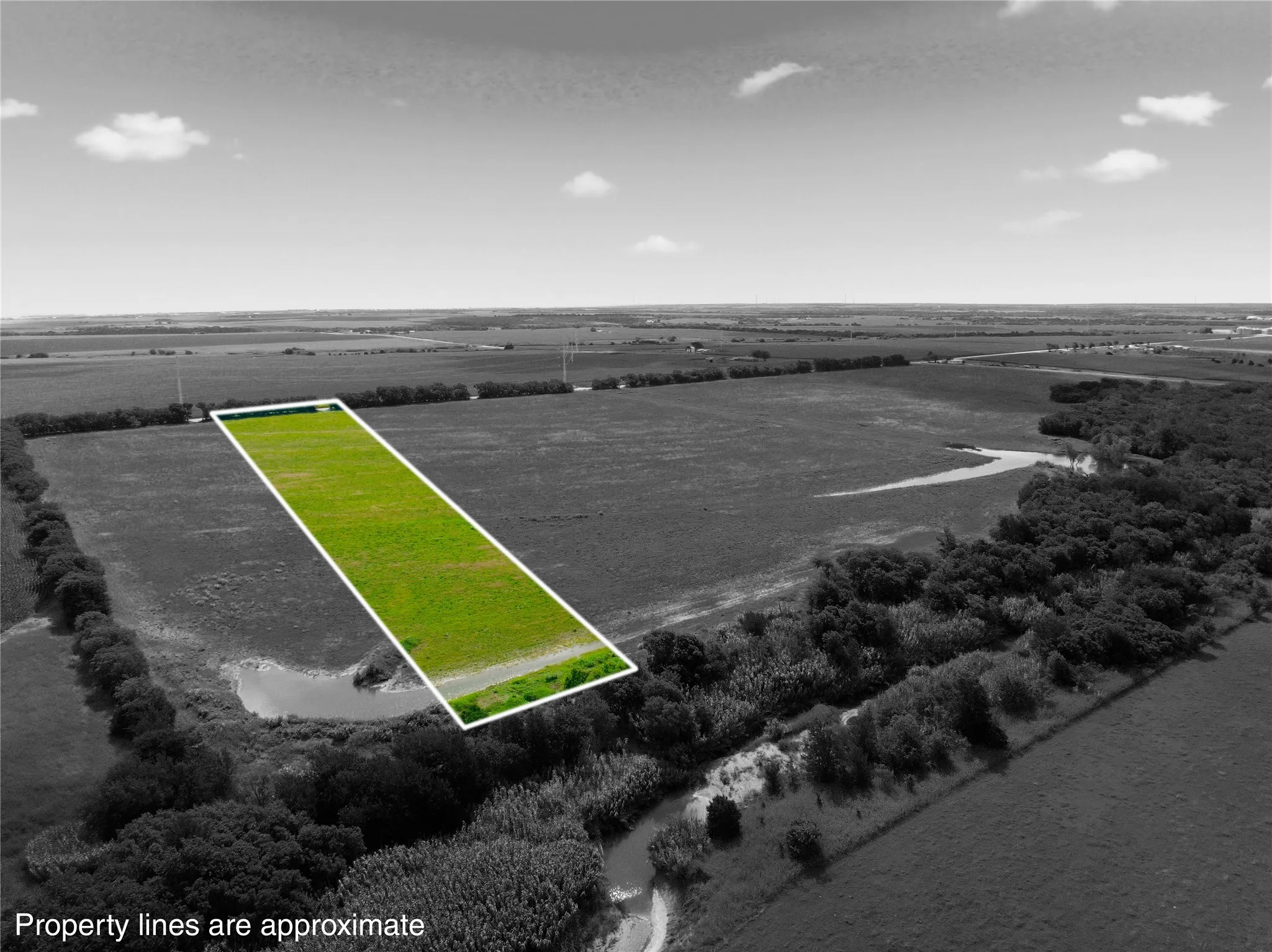 Expansive aerial view of a rectangular plot of land featuring green grass, surrounded by open fields and natural vegetation
