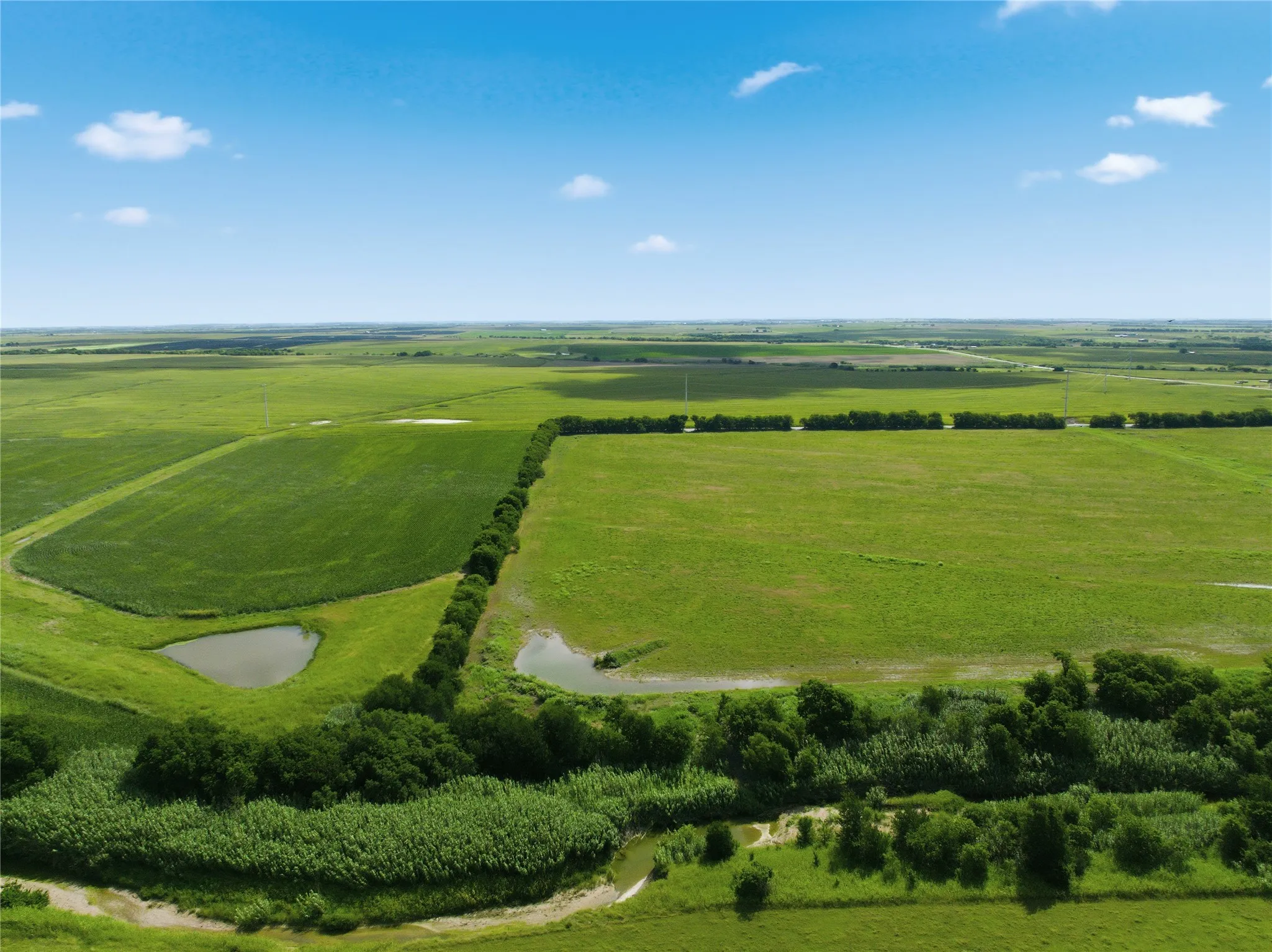 Expansive green fields featuring multiple bodies of water and natural foliage