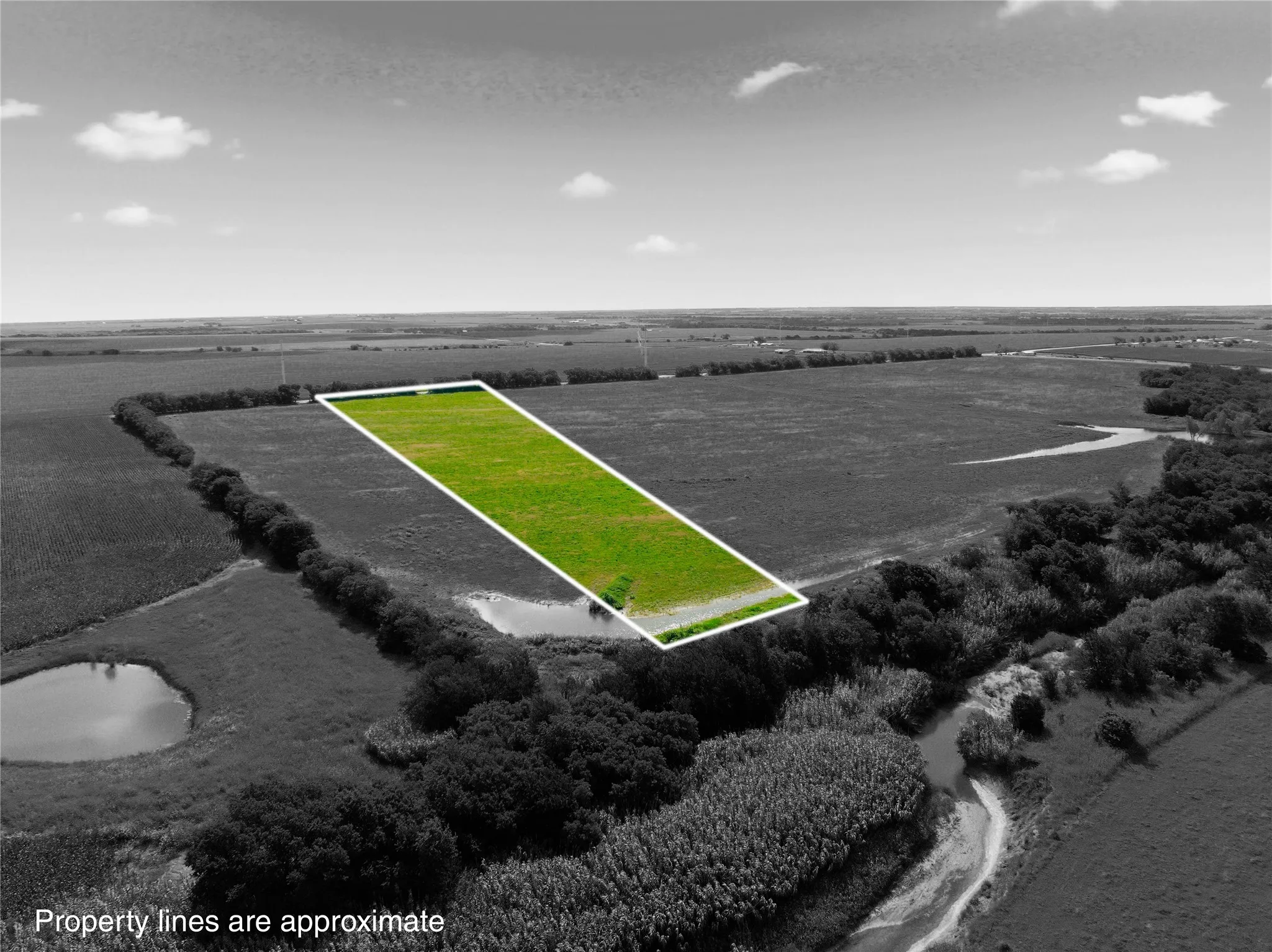 Expansive green lot with clear boundaries, surrounded by natural terrain and distant open fields