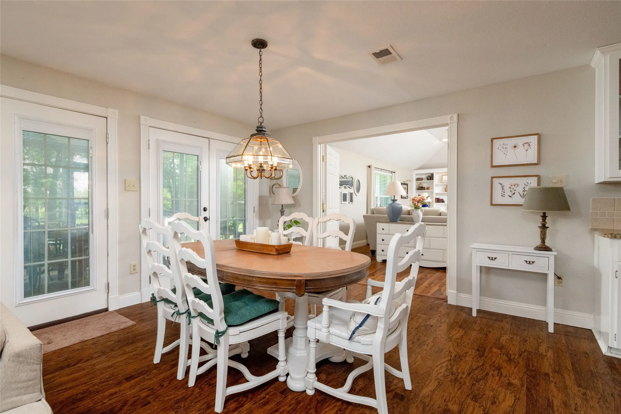 Spacious dining area featuring wood-finish flooring, a decorative chandelier, and double French doors providing exterior access
