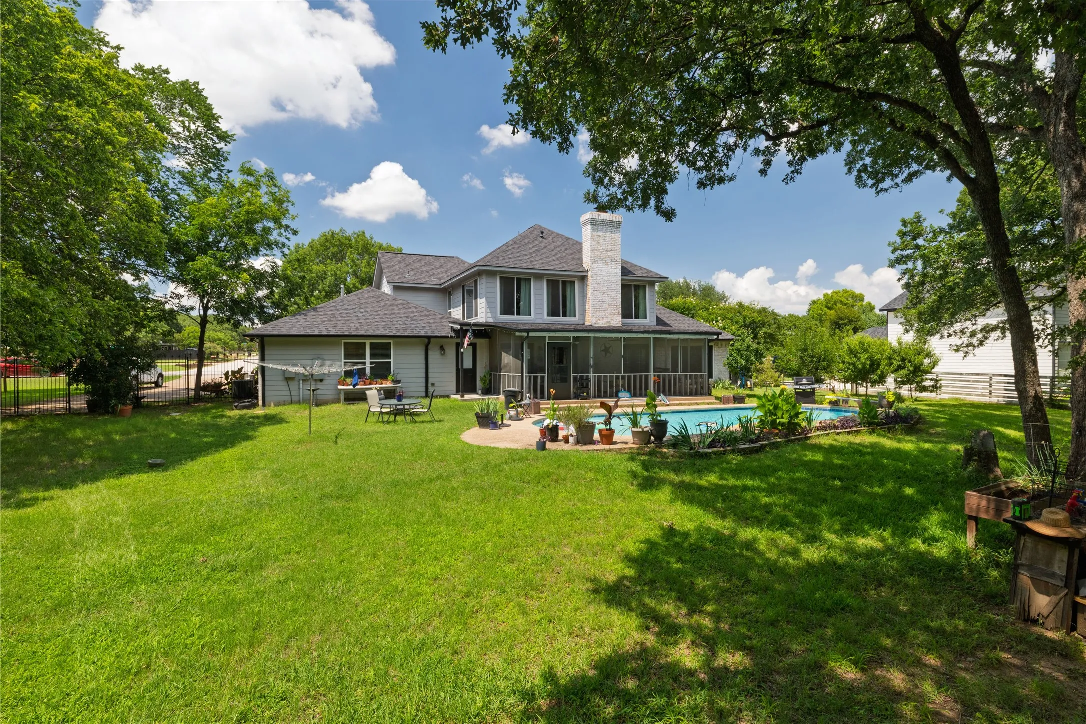 Expansive backyard featuring a large swimming pool, surrounding patio, and a screened-in porch