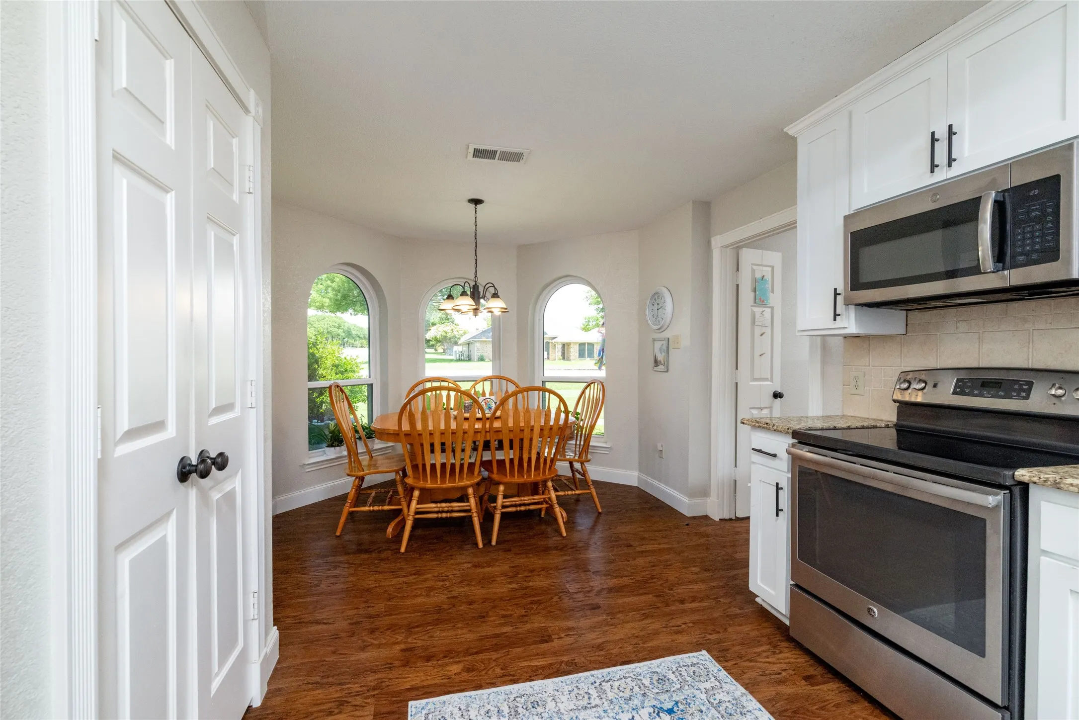 Kitchen with wood-finish flooring, white cabinetry, and stainless steel appliances
