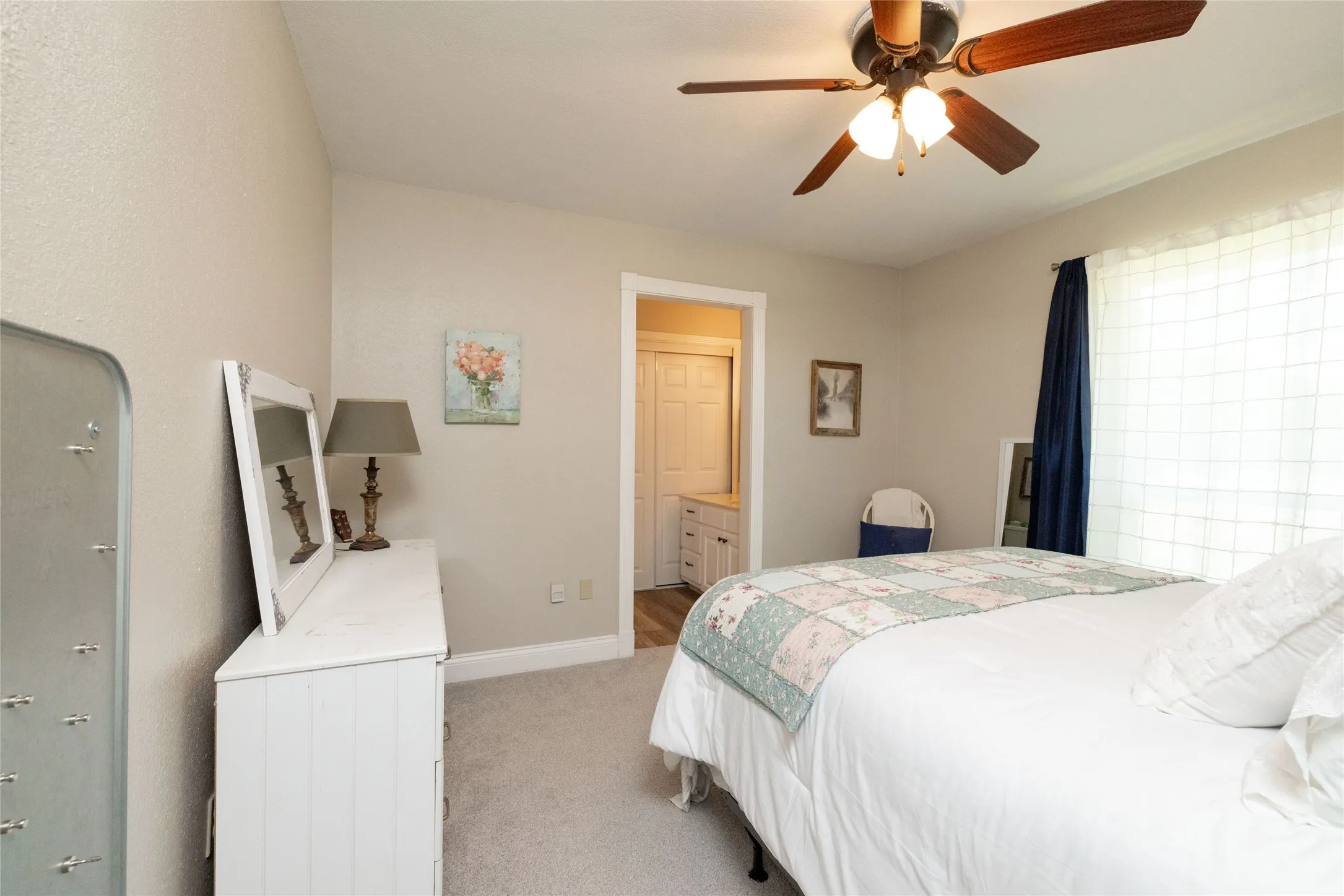 Neutral tone walls featuring a ceiling fan with integrated lighting, window with privacy blinds, and soft carpet flooring