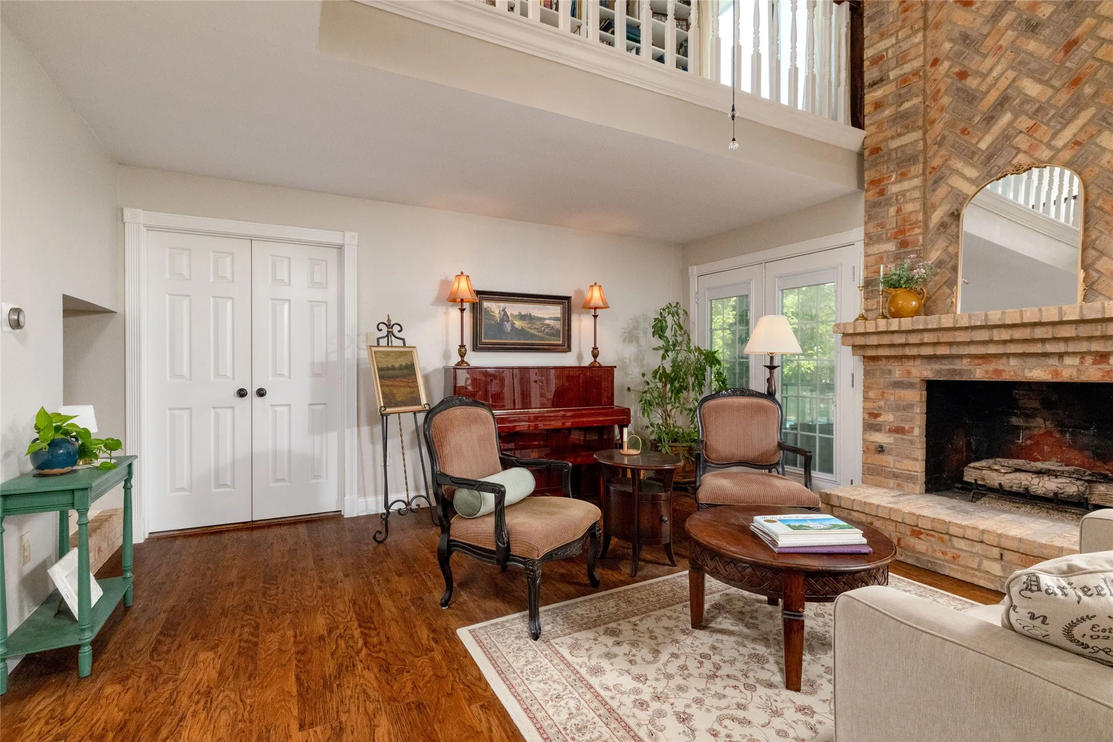 Living area featuring wood-finish flooring, a brick fireplace with hearth, and double French doors providing access to the outdoors
