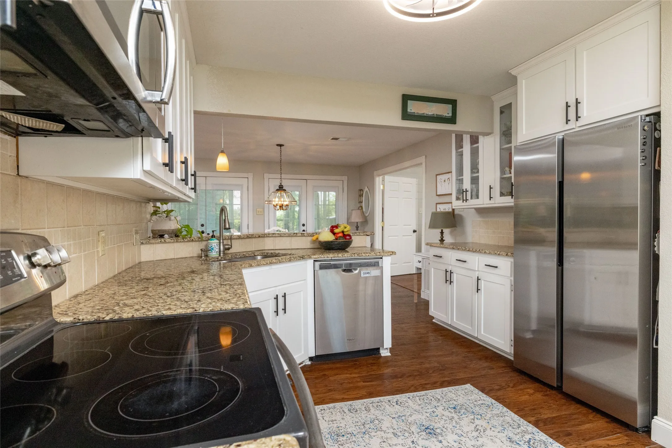 Kitchen featuring white cabinetry, granite countertops, stainless steel appliances, and wood-finish flooring