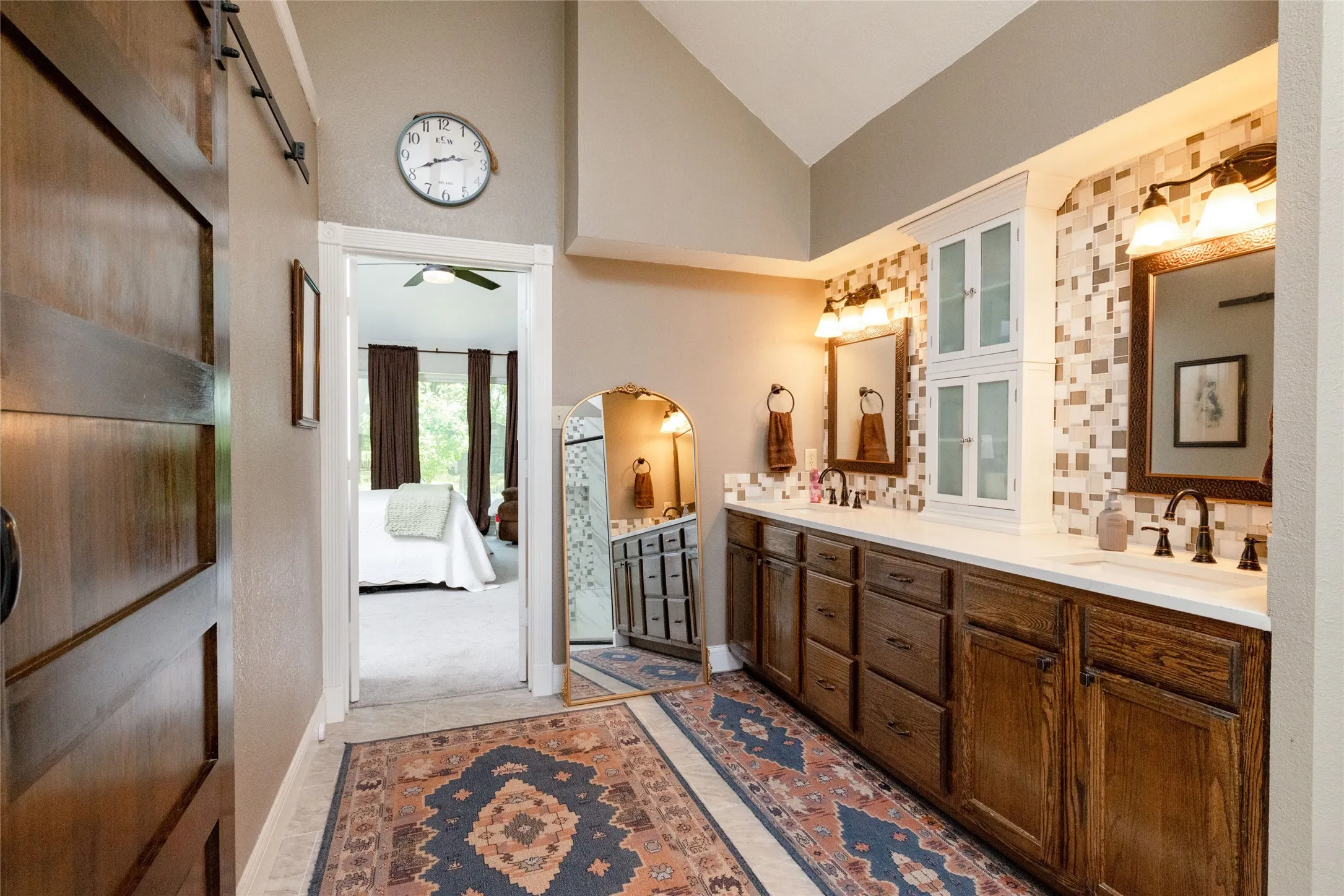 Dual vanity featuring wood cabinetry, white countertops, and mosaic tile backsplash