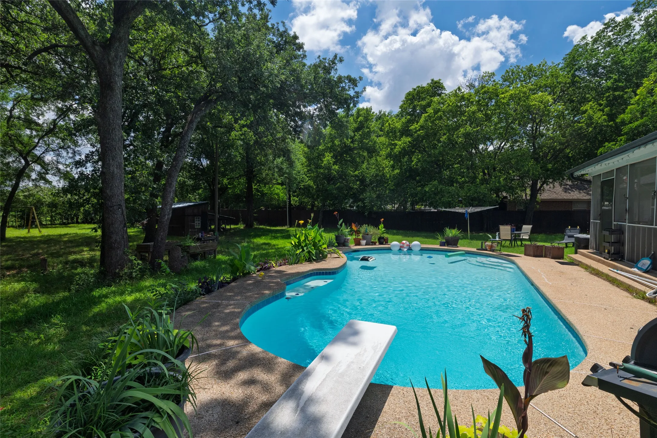 In-ground swimming pool featuring a diving board and integrated steps