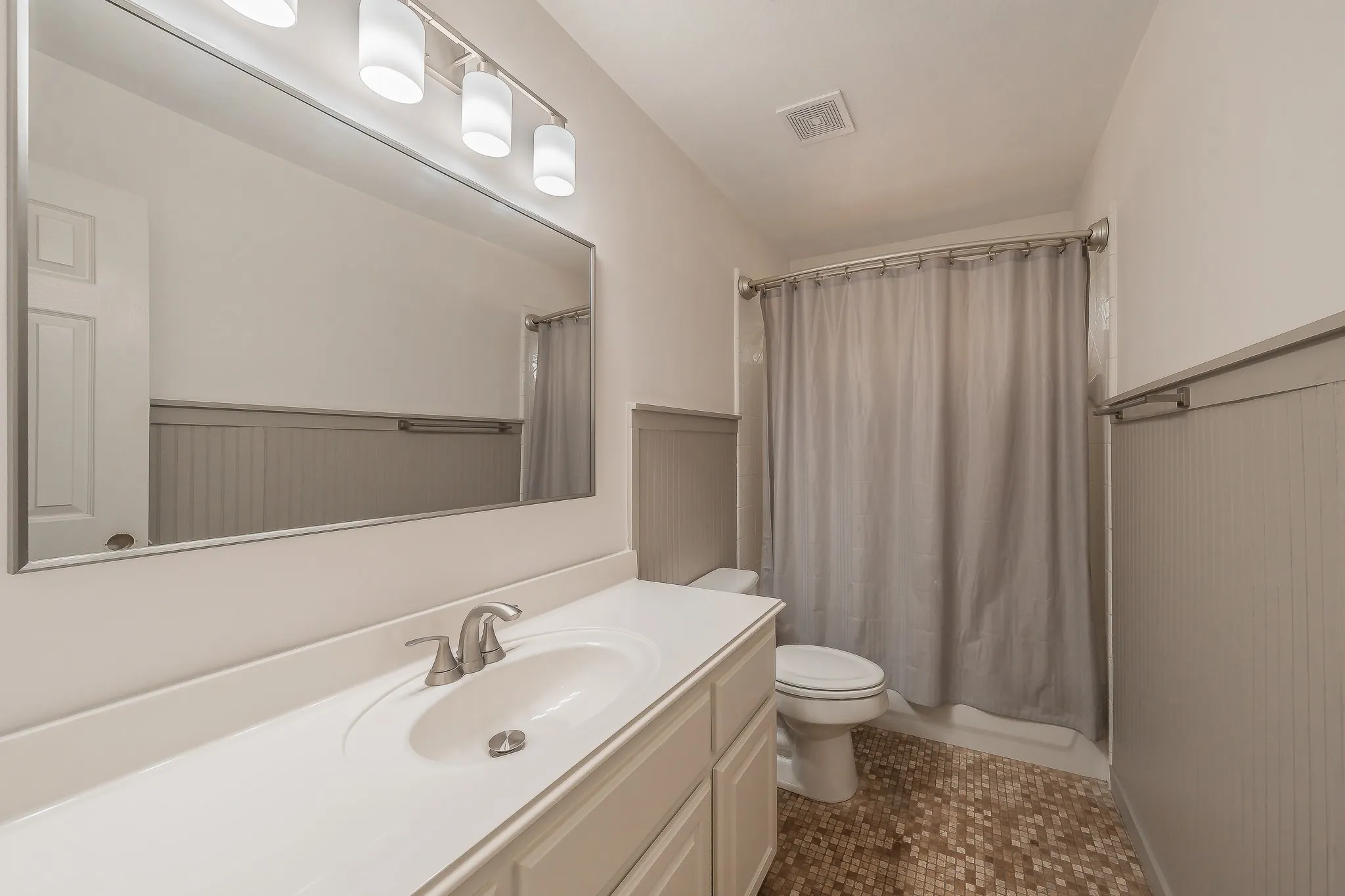 Bathroom featuring a single vanity with an integrated sink, brushed nickel faucet, and a large wall-mounted mirror