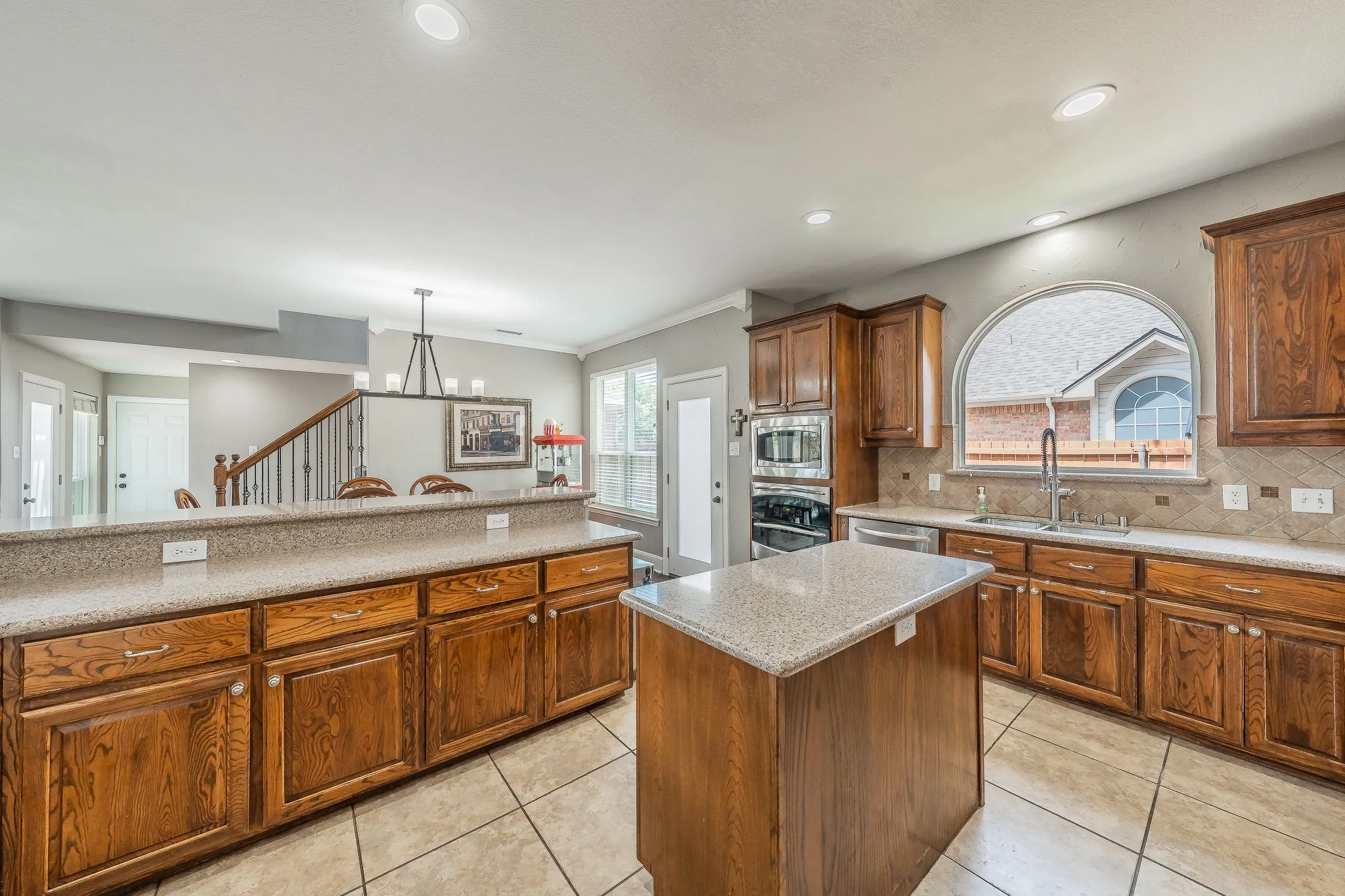 Kitchen featuring wood cabinetry, a center island with countertop, and an arched window above the sink