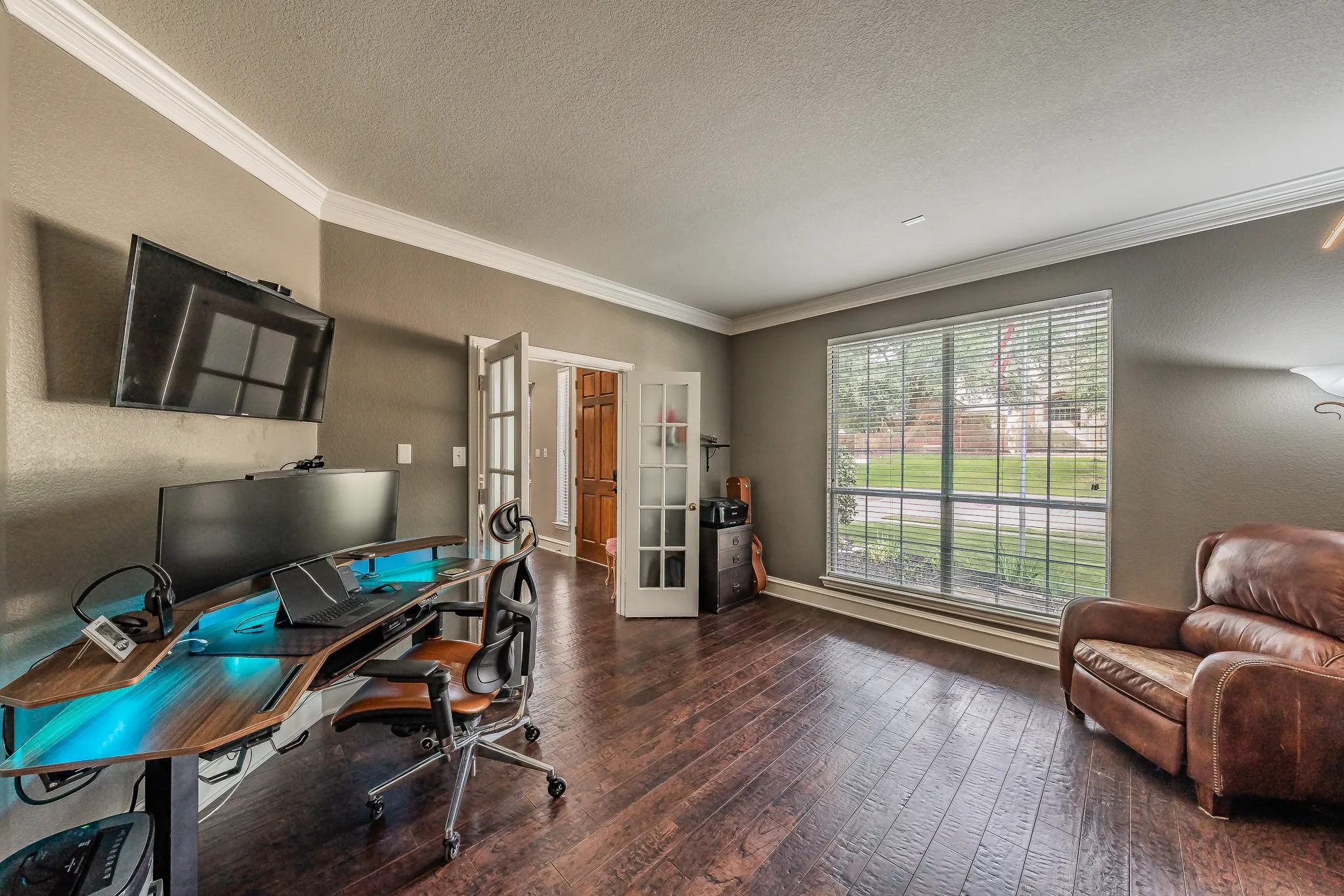 Spacious room featuring wood-finish flooring, neutral wall paint, and white crown molding